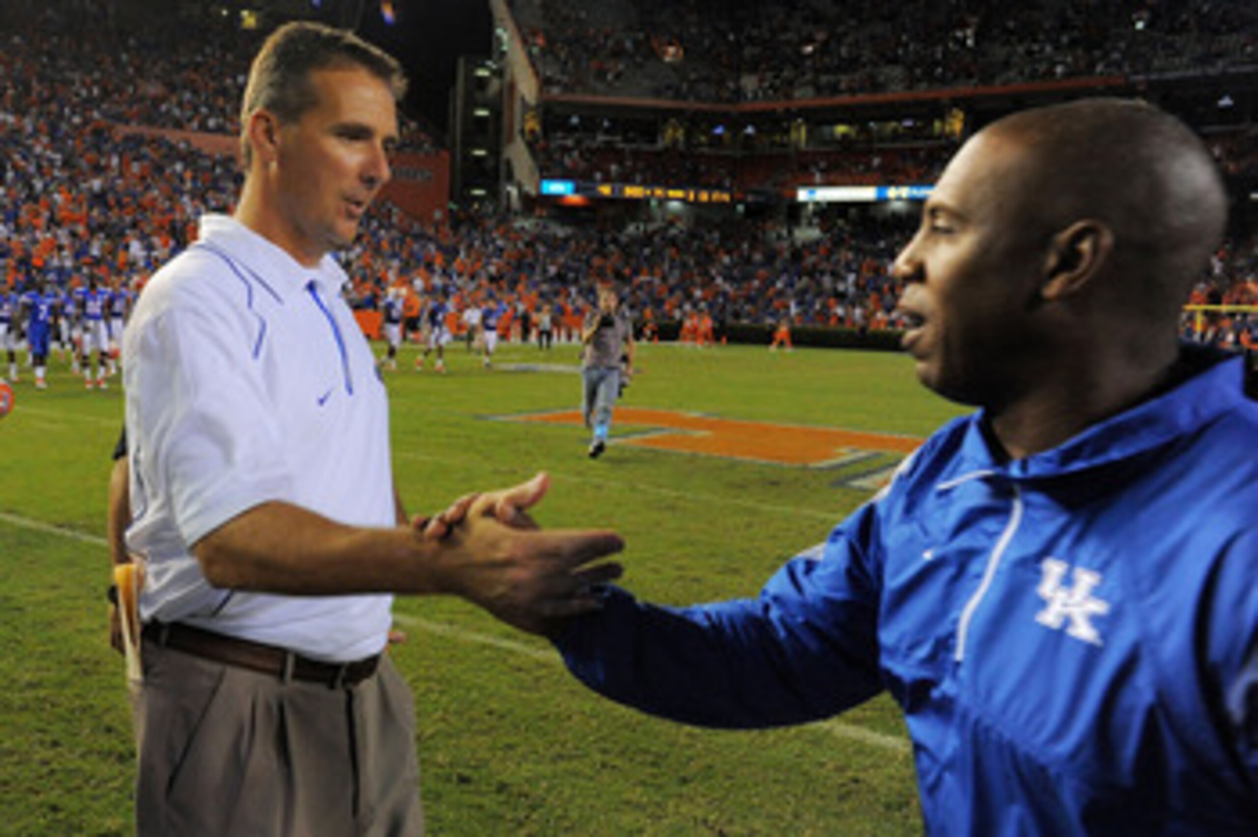 GAINESVILLE, FL - SEPTEMBER 25:  Head coach Urban Meyer of the Florida Gators is congratulated by head coach Joker Phillips of the Kentucky Wildcats at Ben Hill Griffin Stadium on September 25, 2010 in Gainesville, Florida. Florida defeated Kentucky 48-14