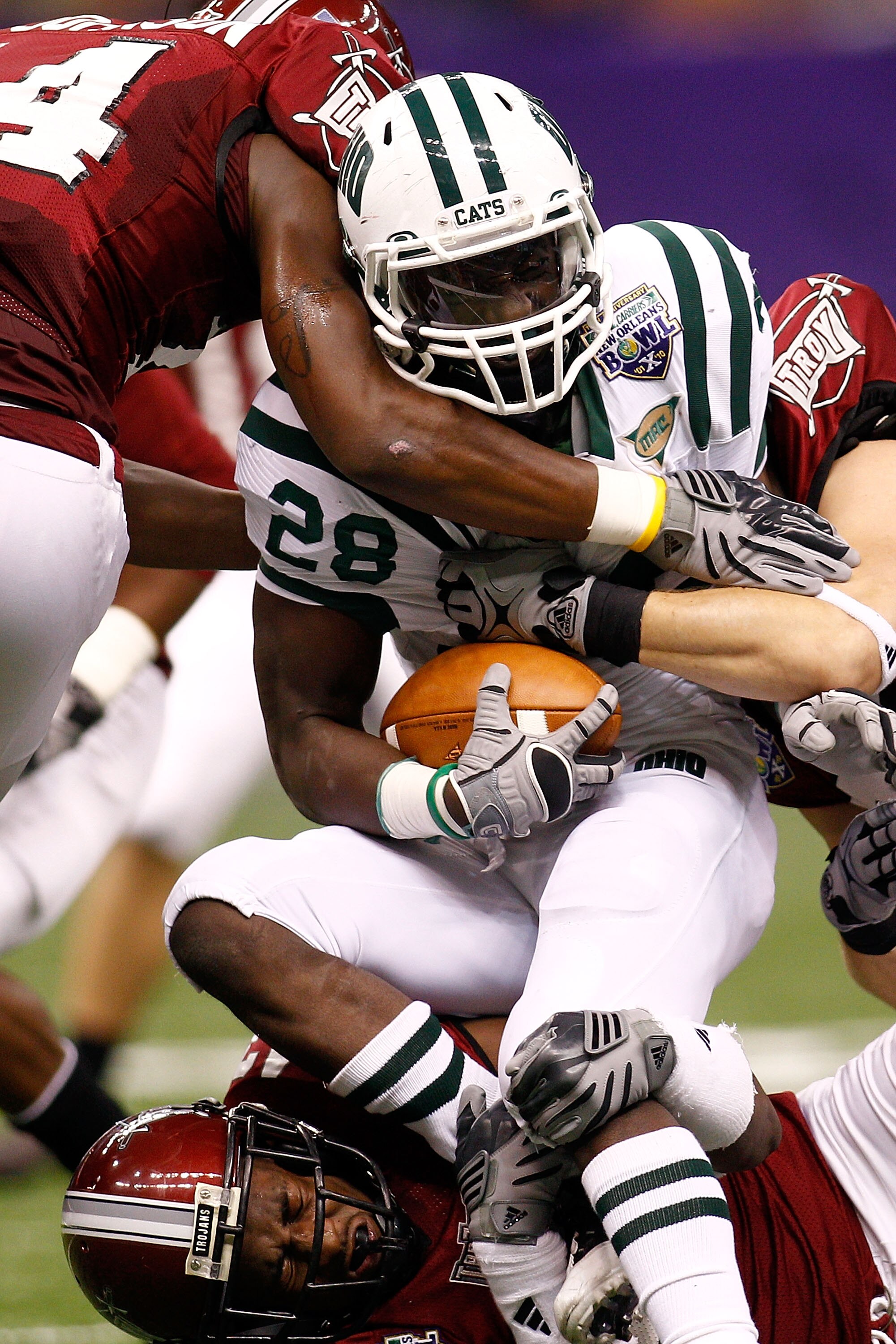 NEW ORLEANS, LA - DECEMBER 18:  Donte Harden #28 of the Ohio University Bobcats is tackled by the Troy University Trojan defense during the R&L Carriers New Orleans Bowl at the Louisiana Superdome on December 18, 2010 in New Orleans, Louisiana.  (Photo by