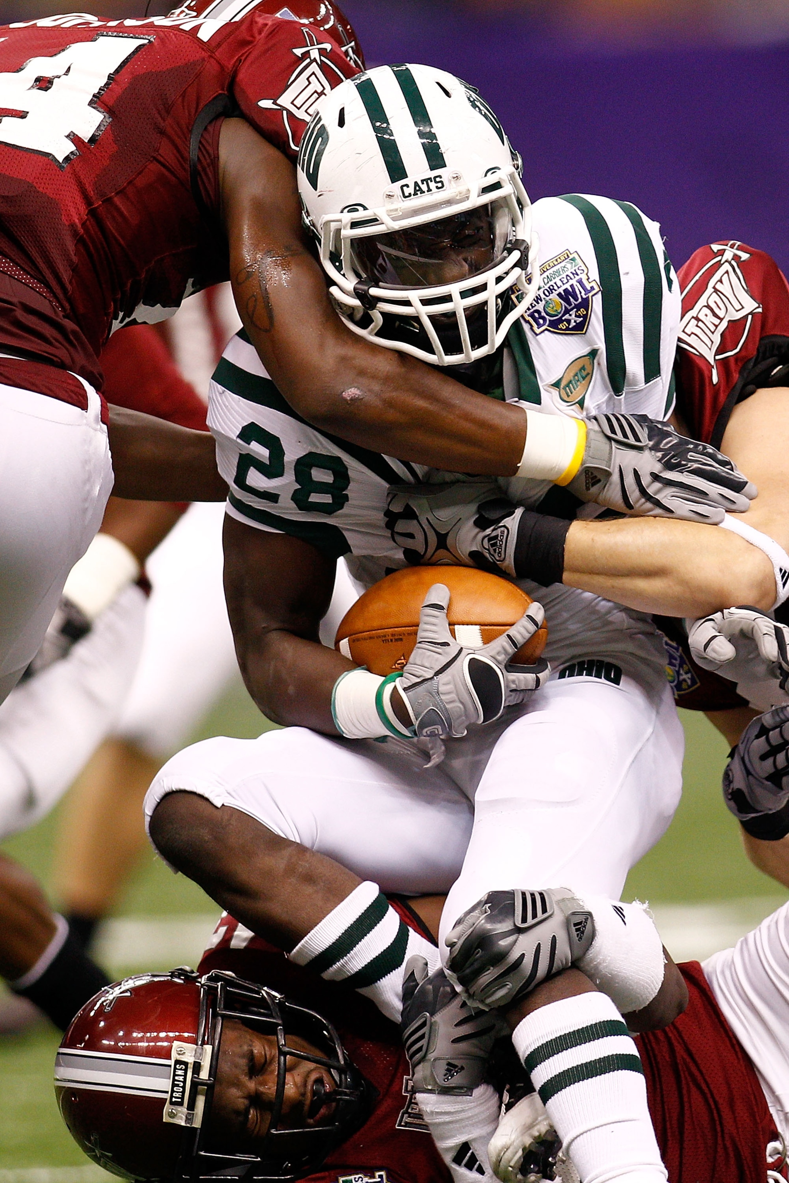 NEW ORLEANS, LA - DECEMBER 18:  Donte Harden #28 of the Ohio University Bobcats is tackled by the Troy University Trojan defense during the R&L Carriers New Orleans Bowl at the Louisiana Superdome on December 18, 2010 in New Orleans, Louisiana.  (Photo by