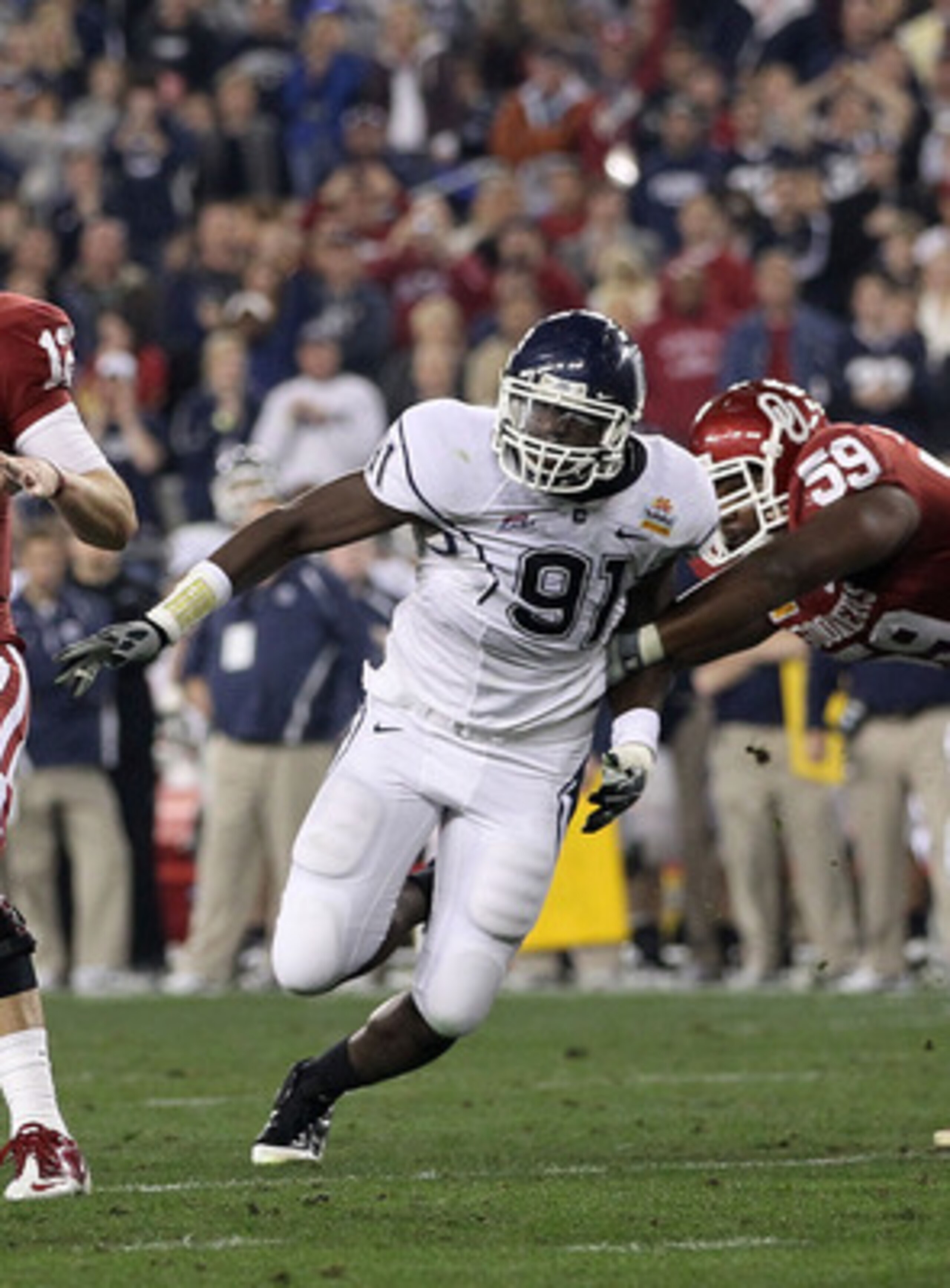 GLENDALE, AZ - JANUARY 01:  Landry Jones #12 of the Oklahoma Sooners passes the ball as Jesse Joseph #91 of the Connecticut Huskies rushes in past Donald Stephenson #59 of the Sooners in the first half against the Connecticut Huskies during the Tostitos F