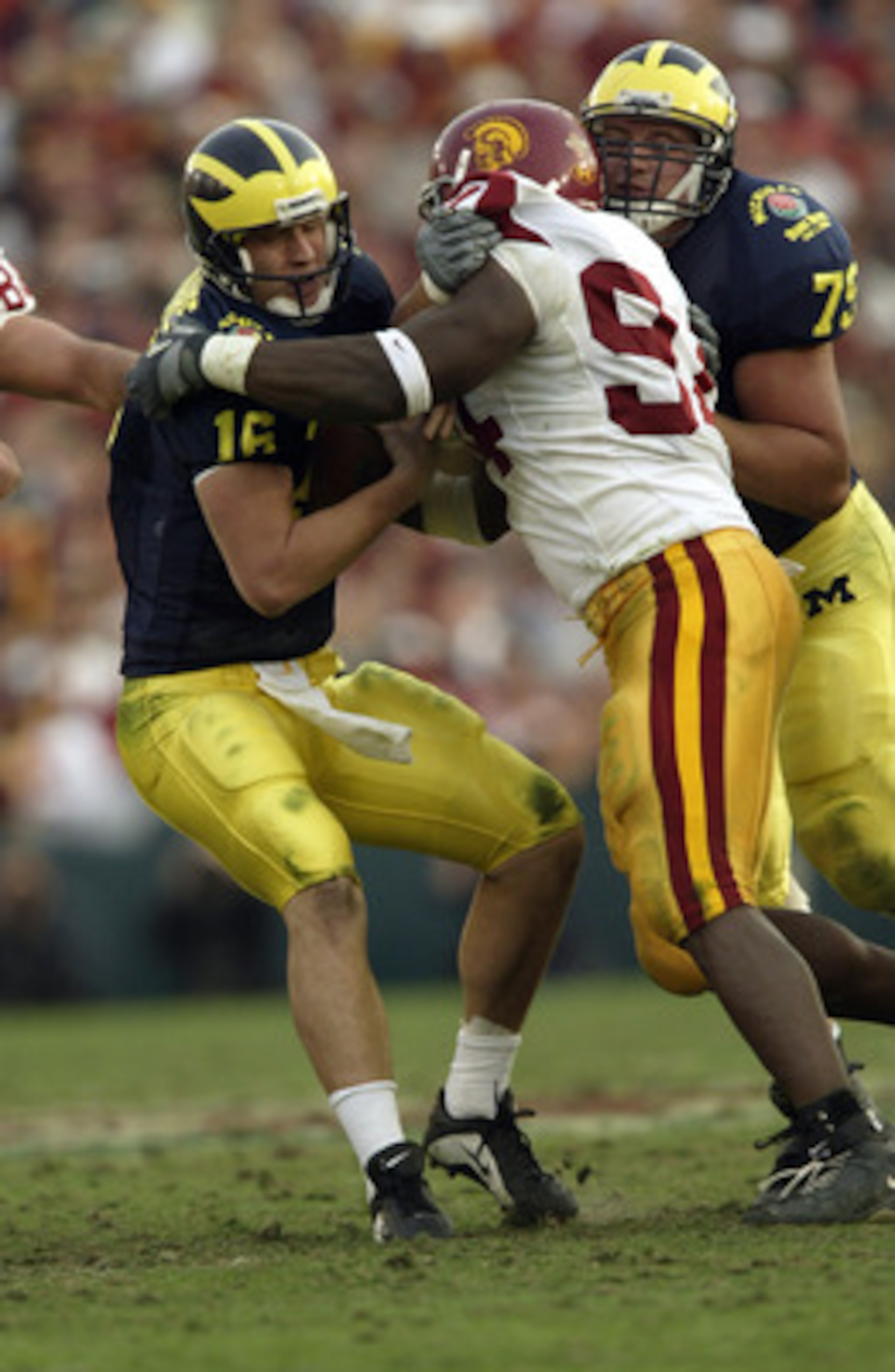 PASADENA, CA - JANUARY 1:  Quarterback John Navarre #16 of the Michigan Wolverines gets sacked down by defensive end Kenechi Udeze #94 of the USC Trojans during the 2004 Rose Bowl game against the USC Trojans on January 1, 2004 at the Rose Bowl in Pasaden