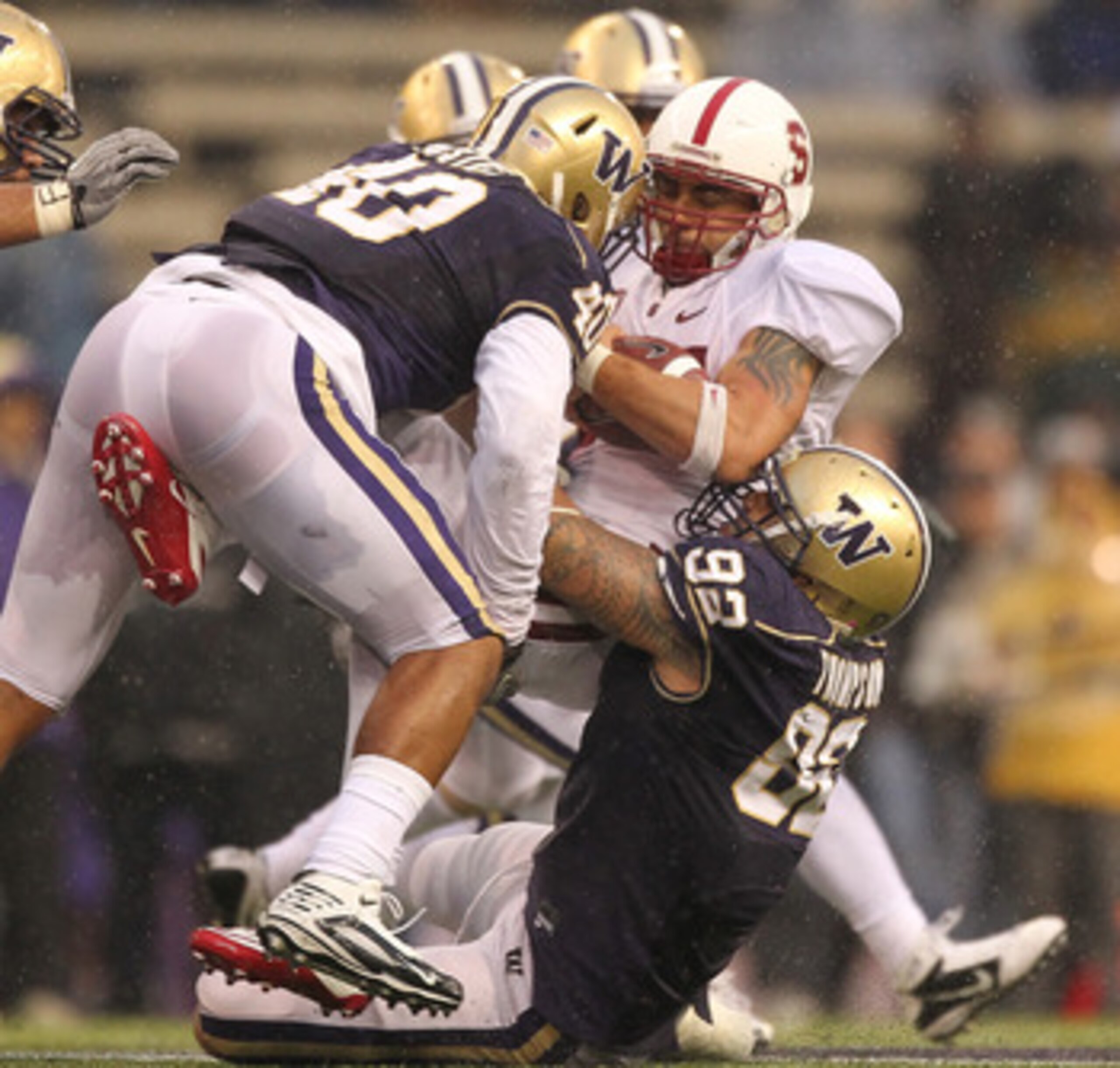 SEATTLE - OCTOBER 30:  Running back Tyler Gaffney #25 of the Stanford Cardinal is tackled by Everrette Thompson #92 and Mason Foster #40 of  the Washington Huskies on October 30, 2010 at Husky Stadium in Seattle, Washington. Stanford defeated Washington 4