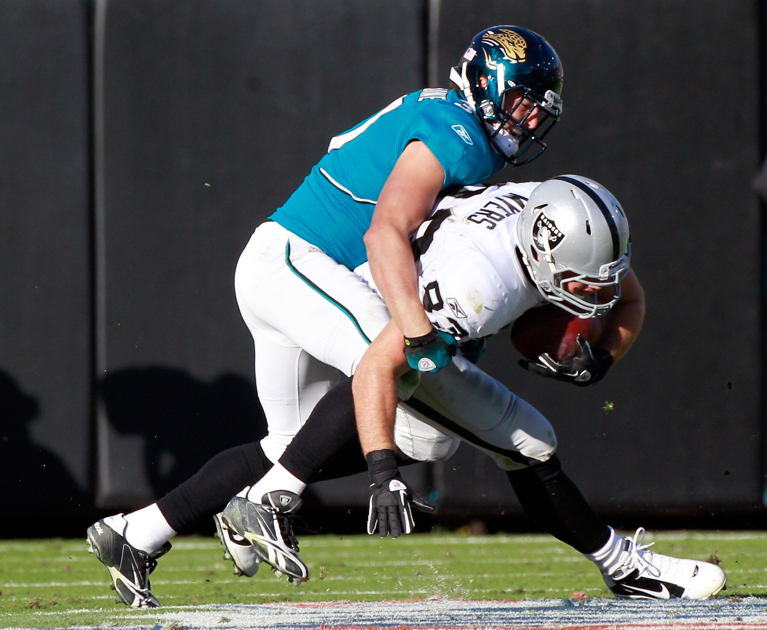 JACKSONVILLE, FL - DECEMBER 12:  Sean Considine #37 of the Jacksonville Jaguars tackles Brandon Myers #83 of the Oakland Raiders during the game at EverBank Field on December 12, 2010 in Jacksonville, Florida.  (Photo by Sam Greenwood/Getty Images)