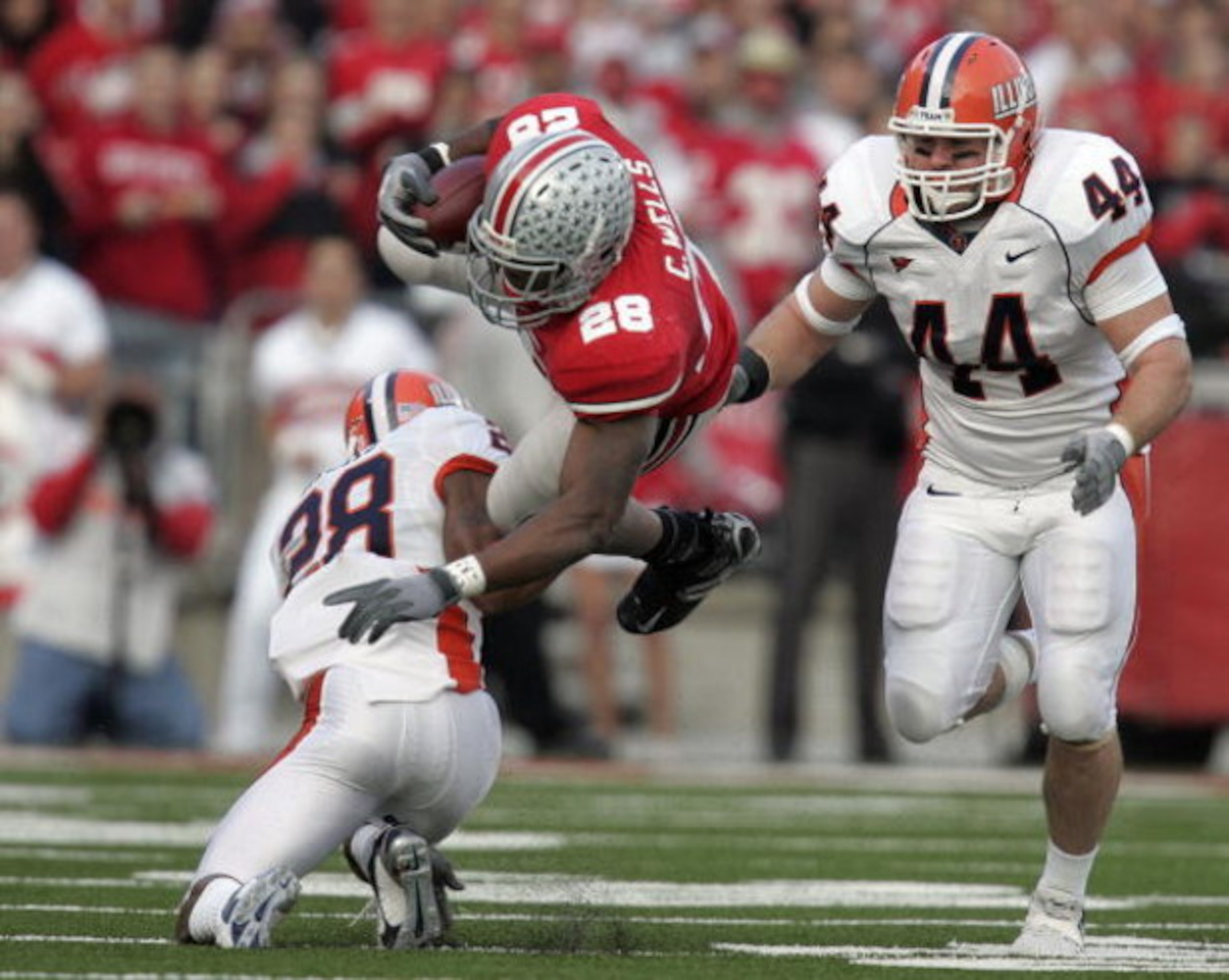 COLUMBUS - NOVEMBER 10:  Chris Wells #28 of the Ohio State Buckeyes is tackled by Dere Hicks #28 of the Illinois Fighting Illini as Illinois player Brit Miller #44 looks on during the first quarter at Ohio Stadium November 10, 2007 in Columbus, Ohio. Illi