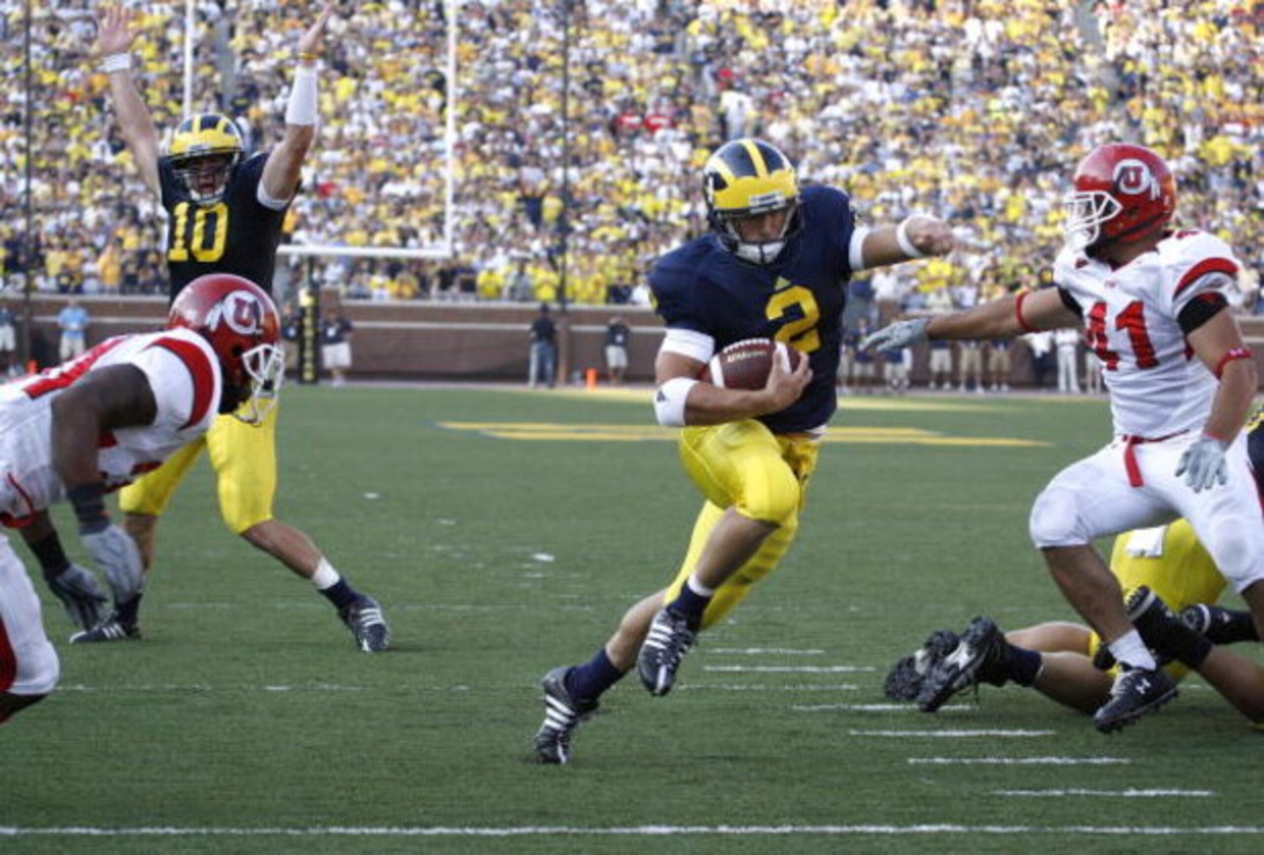 ANN ARBOR, MI - AUGUST 30:  Sam McGuffie #2 of the Michigan Wolverines runs for a fourth quarter touchdown past Koa Misi #41 with Steven Threet #10 celebrating in the background on August 30, 2008 at Michigan Stadium in Ann Arbor, Michigan. Utah won the g