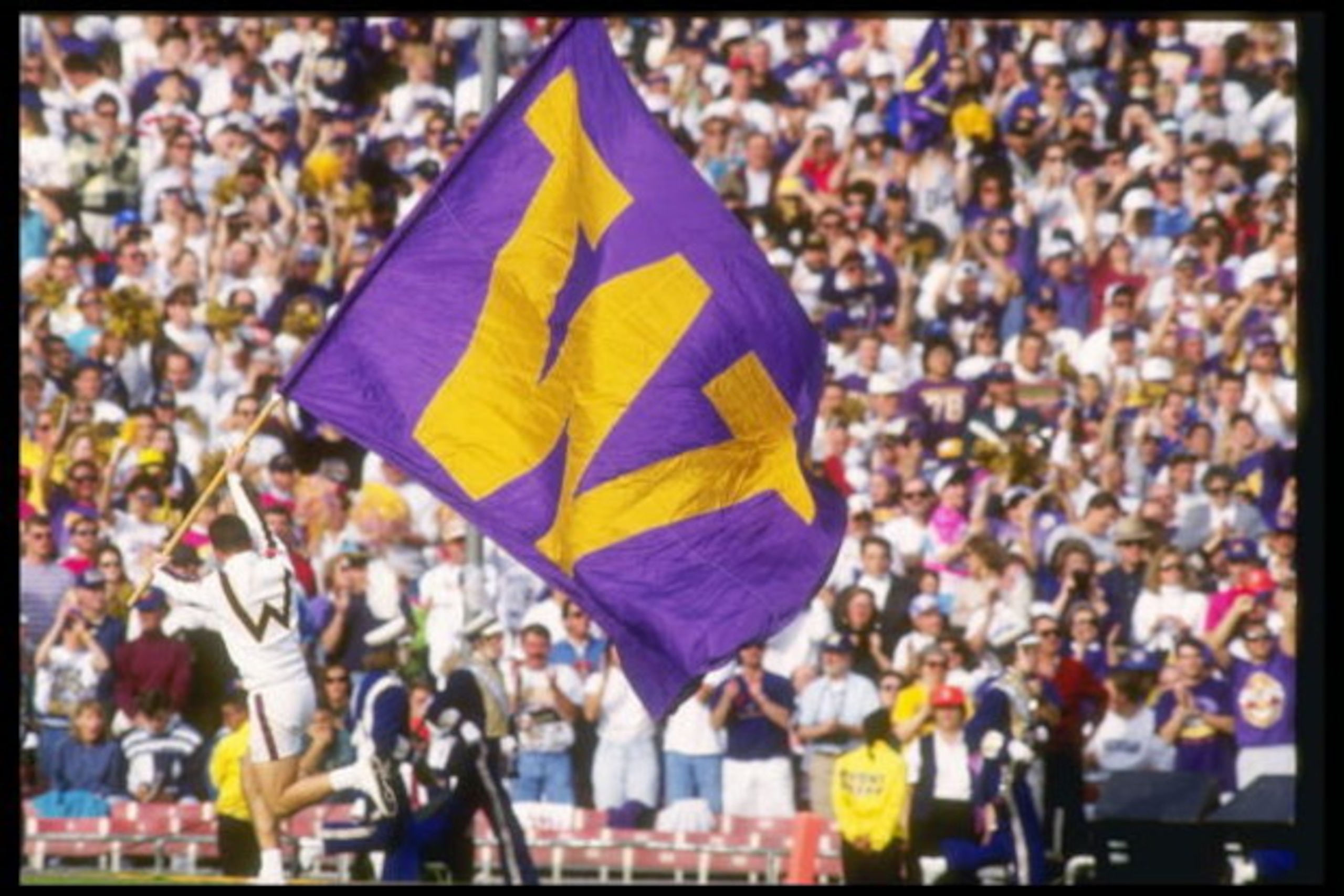 1992 Jan 1: Univeristy of Washington Huskies cheerleader runs across the field with the school flag prior to start of the 1992 Rose Bowl against the University of Michigan Wolverines at the Rose Bowl in Pasadena, California. The University of Washington 1992 Jan 1: Univeristy of Washington Huskies cheerleader runs across the field with the school flag prior to start of the 1992 Rose Bowl against the University of Michigan Wolverines at the Rose Bowl in Pasadena, California. The University of Washington