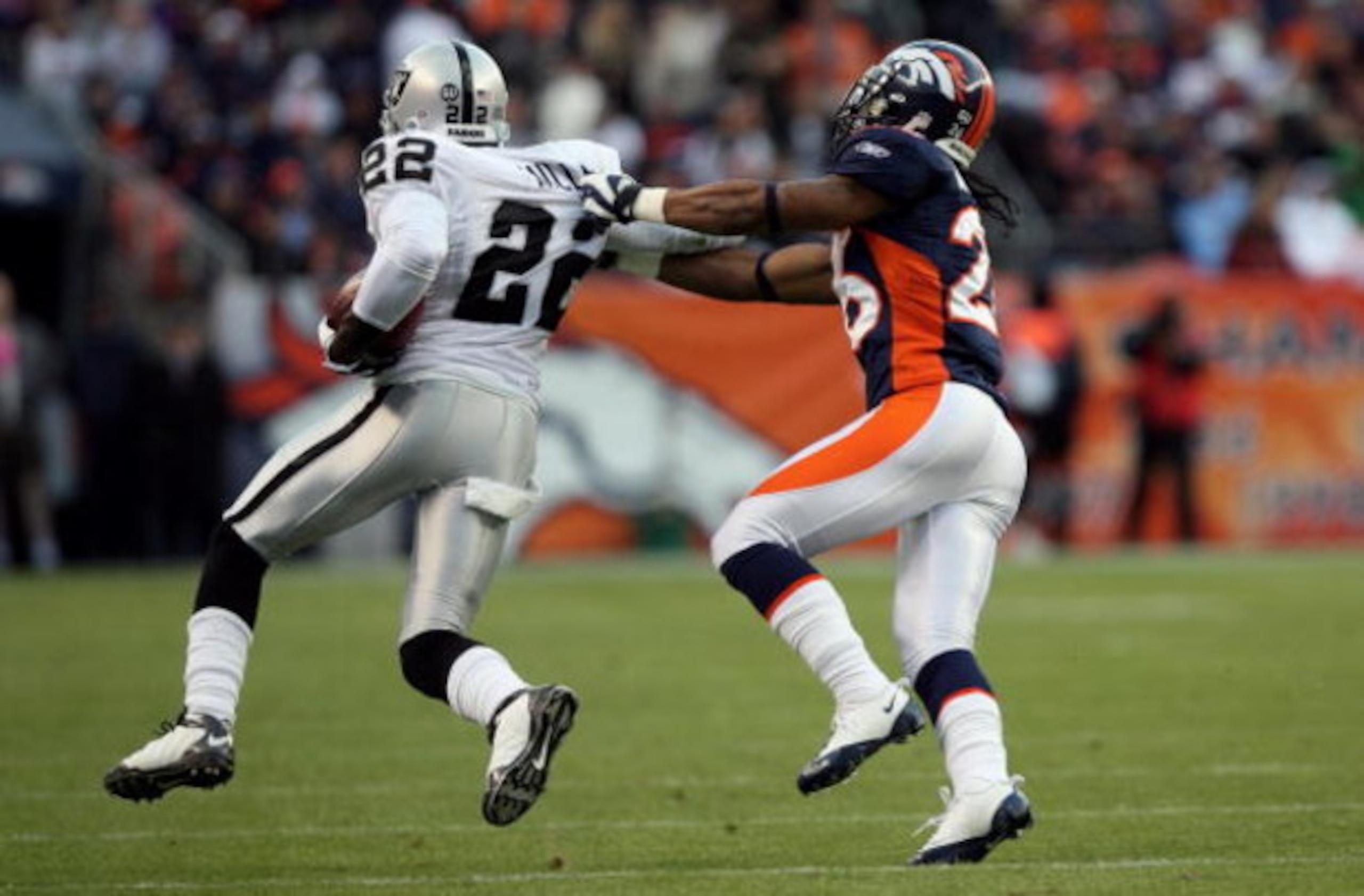 DENVER - NOVEMBER 23:  Justin Miller #22 of the Oakland Raiders returns the a kick off as Jack Williams #26 of the Denver Broncos makes the tackle during week 12 NFL action at Invesco Field at Mile High on November 23, 2008 in Denver, Colorado. The Raider