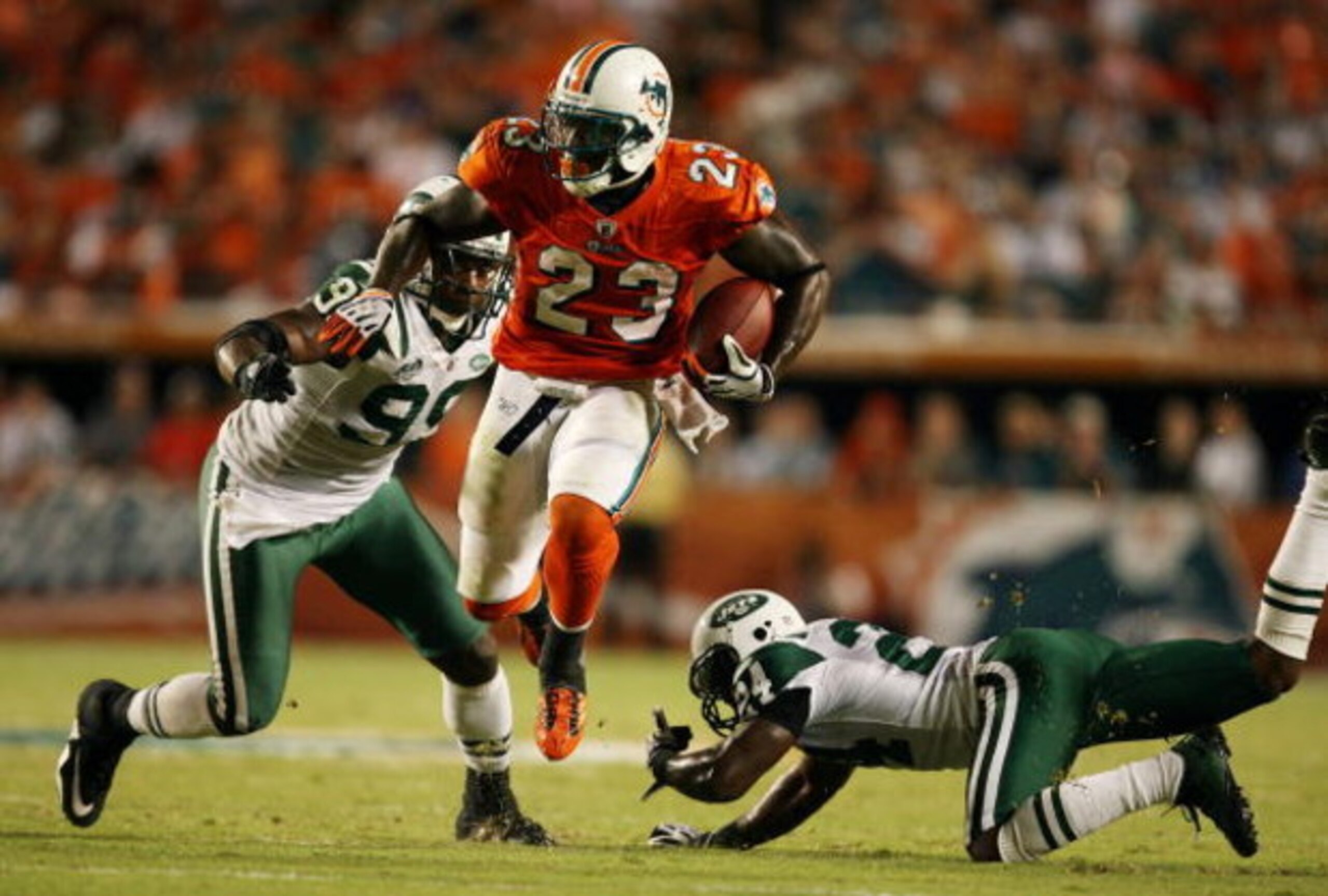 MIAMI - OCTOBER 12: Running back Ronnie Brown #23 of the Miami Dolphins jumps between linebacker Bryan Thomas #99 and cornerback Darrelle Revis #24 of the New York Jets at Land Shark Stadium on October 12, 2009 in Miami, Florida. The Dolphins defeated th MIAMI - OCTOBER 12: Running back Ronnie Brown #23 of the Miami Dolphins jumps between linebacker Bryan Thomas #99 and cornerback Darrelle Revis #24 of the New York Jets at Land Shark Stadium on October 12, 2009 in Miami, Florida. The Dolphins defeated th