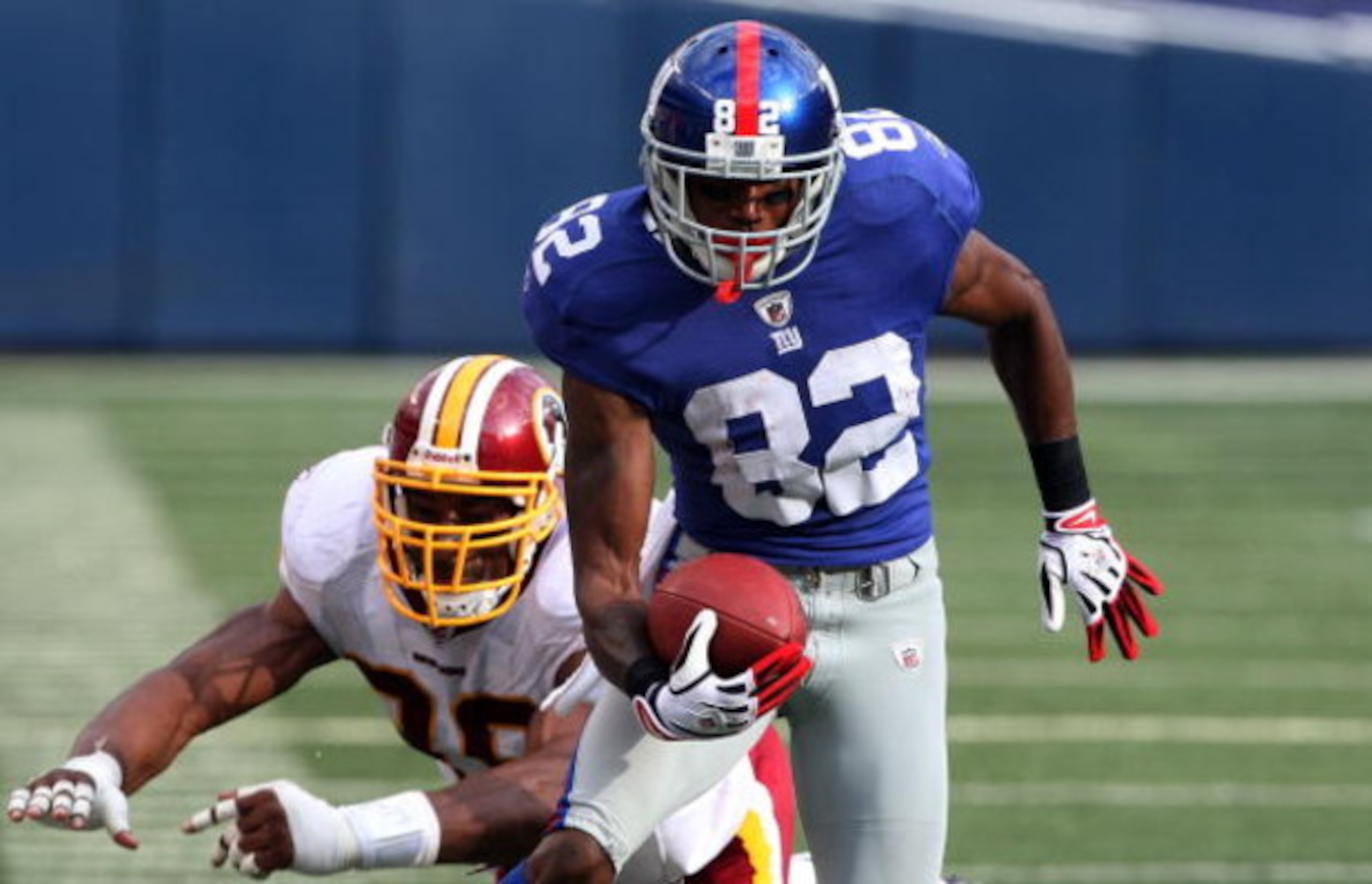 EAST RUTHERFORD, NJ - SEPTEMBER 13:  Mario Manningham #82 of the New York Giants eludes a tackle attempt from Andre Carter #99 of the Washington Redskins enroute to a touchdown on September 13, 2009 at Giants Stadium in East Rutherford, New Jersey.  (Phot