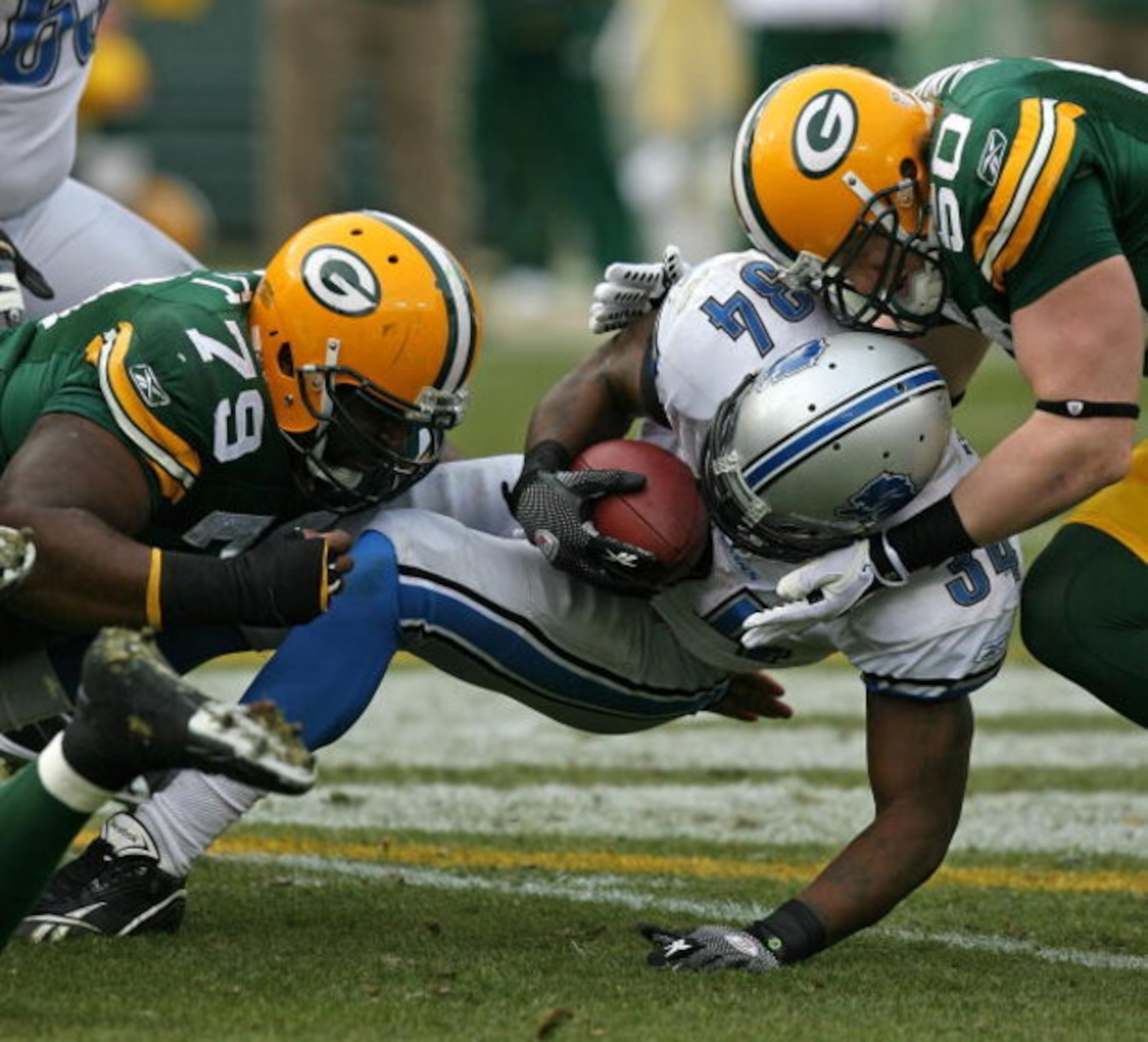 GREEN BAY, WI - OCTOBER 18: Kevin Smith #34 of the Detroit Lions is tackled by Ryan Pickett #79 and A.J. Hawk #50 of the Green Bay Packers at Lambeau Field on October 18, 2009 in Green Bay, Wisconsin. The Packers defeated the Lions 26-0. (Photo by Jonatha