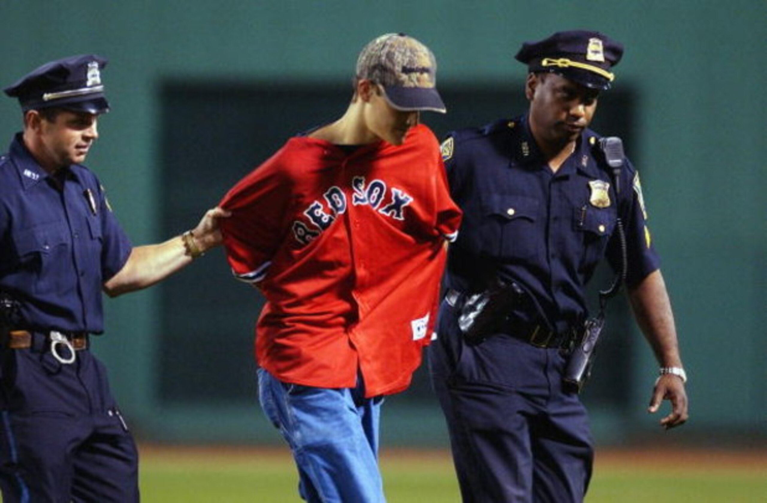 BOSTON, MA- AUGUST 24:  Red Sox fan is escorted off the field by authorities during the game between the Seattle Mariners and the Boston Red Sox on August 24, 2003 at Fenway Park in Boston, Massachusetts. The Red Sox defeated the Mariners 6-1. (Photo by D