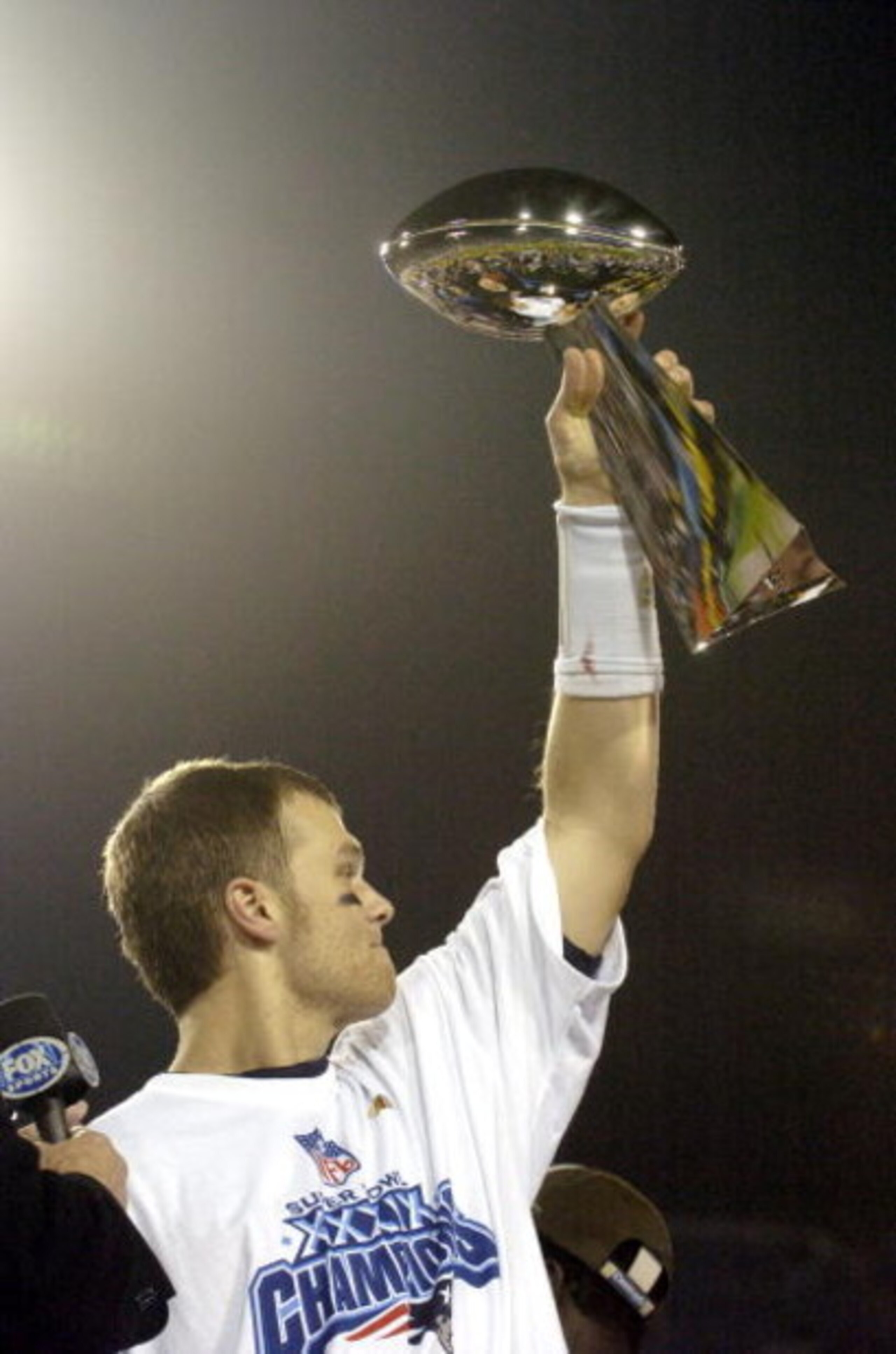 Tom Brady holds the Vince Lombardi Trophy as he stands on the podium after The New England Patriots defeated The Philadelphia Eagles in Super Bowl XXXIX at Alltel Staduim in Jacksonville, Florida.  (Photo by Al Messerschmidt/Getty Images)