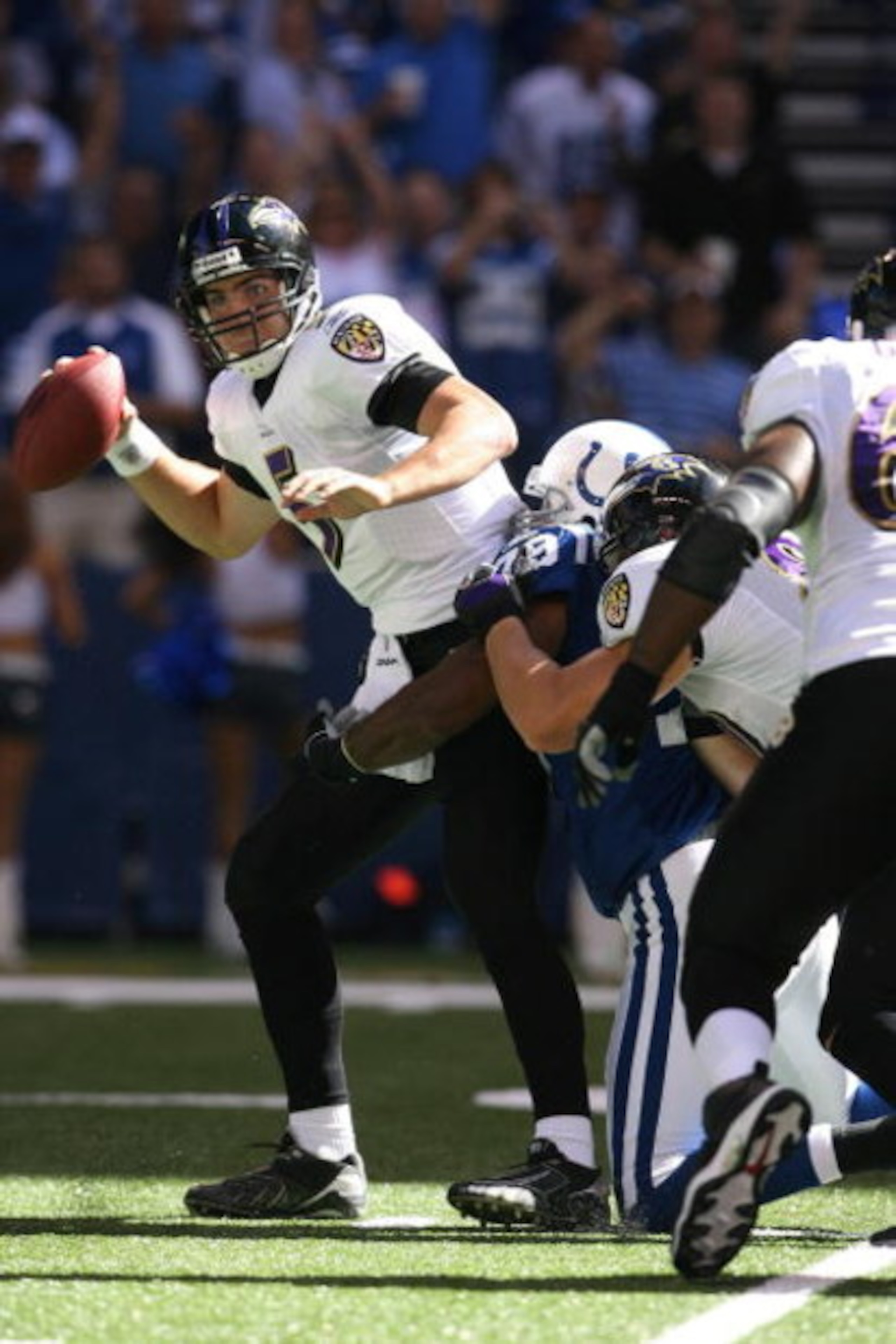 INDIANAPOLIS - OCTOBER 12:  Quarterback Joe Flacco #5 of the Baltimore Ravens looks to get rid of the ball as he's being tackled during the NFL game against the Indianapolis Colts at Lucas Oil Stadium on October 12, 2008 in Indianapolis, Indiana. The Colt