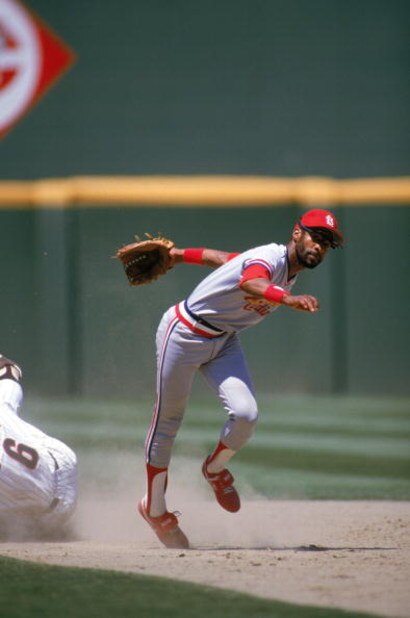 SAN DIEGO - 1985:  Ozzie Smith #1 of the St. Louis Cardinals stumbles after dodging a sliding San Diego Padres base runner during a game in 1985 at Jack Murphy Stadium in San Diego, California.  (Photo by Stephen Dunn/Getty Images)      