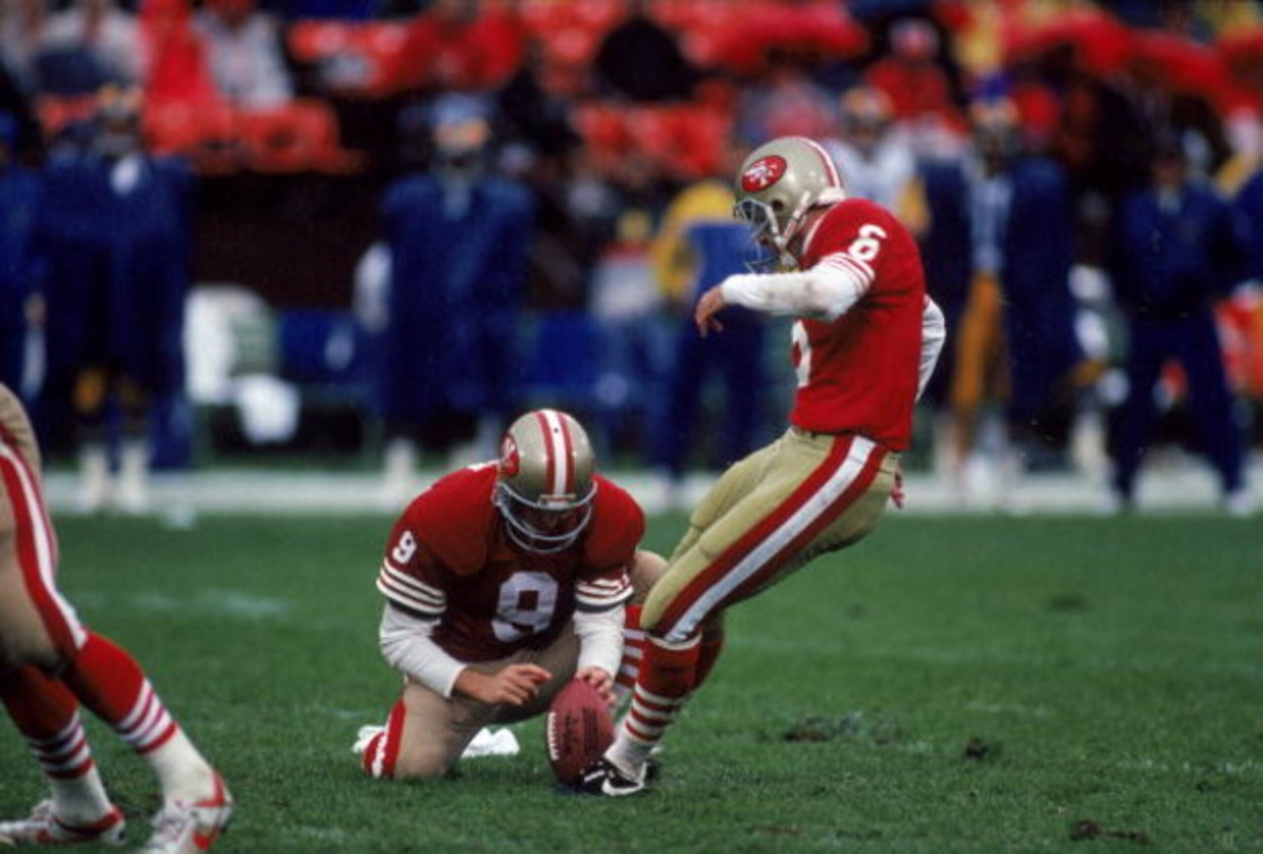SAN FRANCISCO - NOVEMBER 25: Kicker Mike Cofer #6 holds the ball as teammate Barry Helton #9 of the San Francisco 49ers follows through on his kick during a game against the Los Angeles Rams at Candlestick Park on November 25, 1990 in San Francisco, Cali SAN FRANCISCO - NOVEMBER 25: Kicker Mike Cofer #6 holds the ball as teammate Barry Helton #9 of the San Francisco 49ers follows through on his kick during a game against the Los Angeles Rams at Candlestick Park on November 25, 1990 in San Francisco, Cali