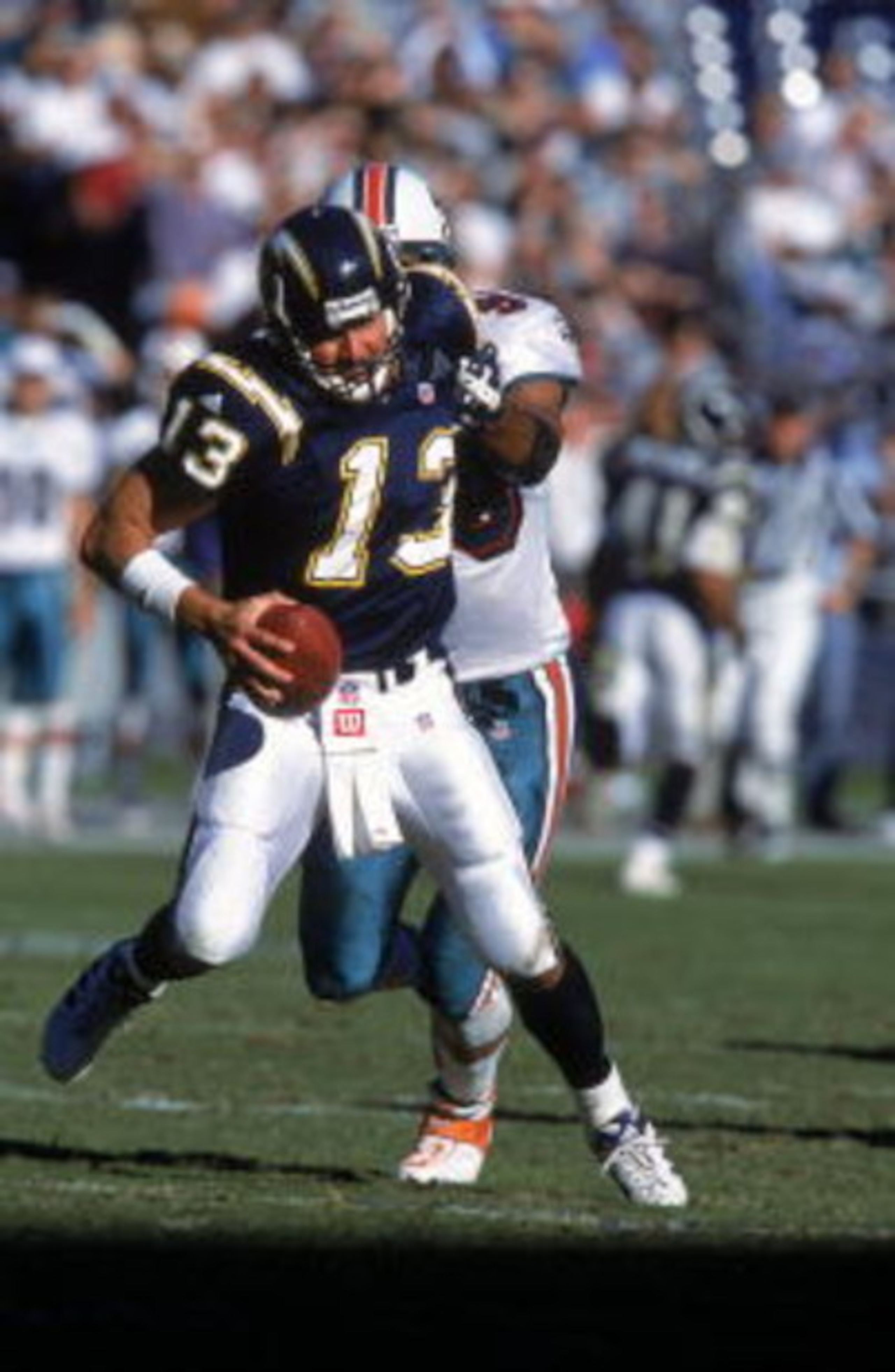 SAN DIEGO - NOVEMBER 12:  Quarterback Moses Moreno #13 of the San Diego Chargers scrambles as he is sacked by Jason Taylor #99 of the Miami Dolphins on November 12, 2000 at Qualcomm Stadium in San Diego, California.  The Dolphins defeated the Chargers 17-