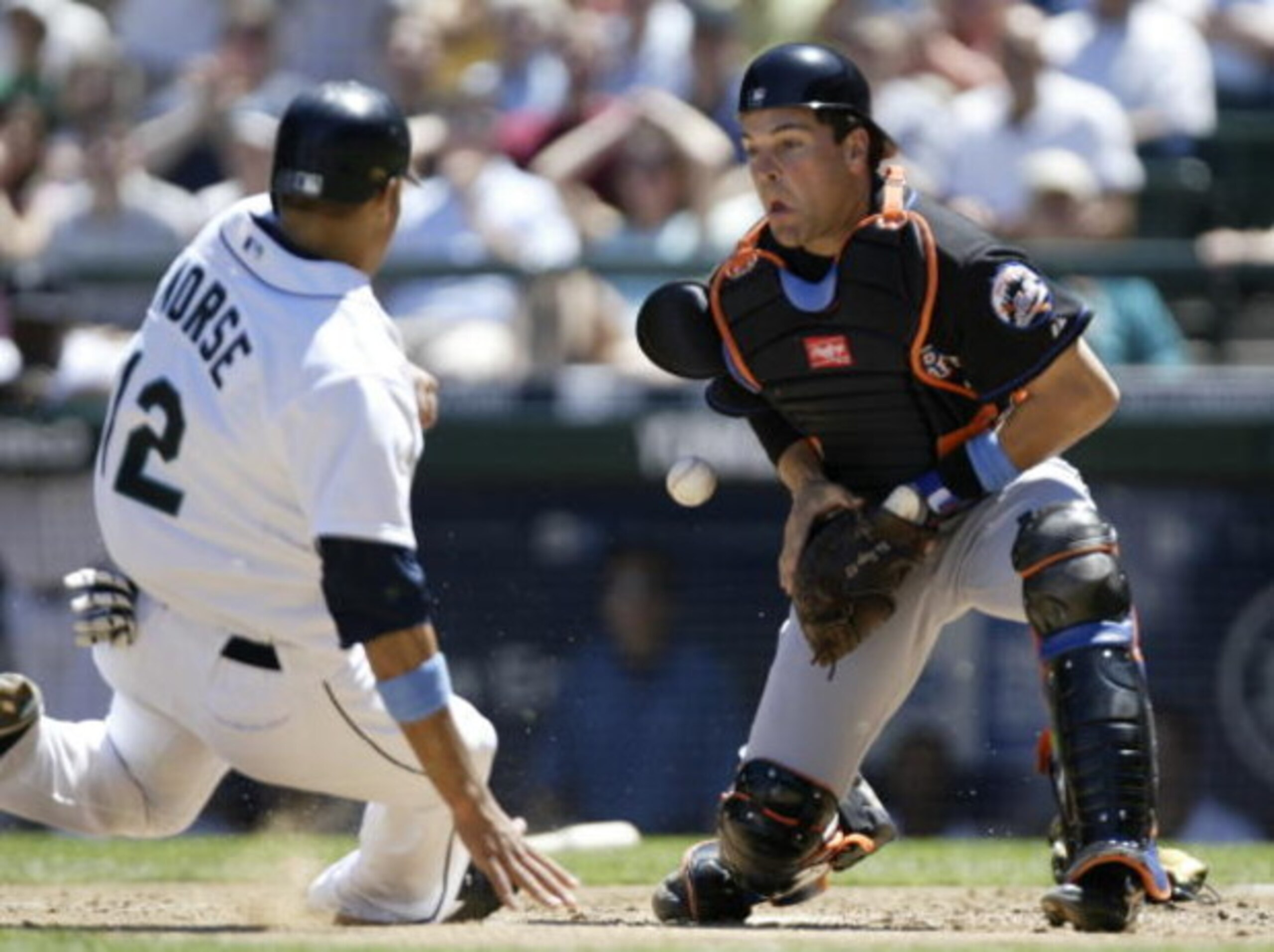 SEATTLE - JUNE 19:  Mike Morse #12 of the Seattle Mariners scores a run sliding into home plate ahead of the throw to catcher Mike Piazza #31 of the New York Mets in the second inning on June 19, 2005 at Safeco Field in Seattle, Washington. The Mariners d