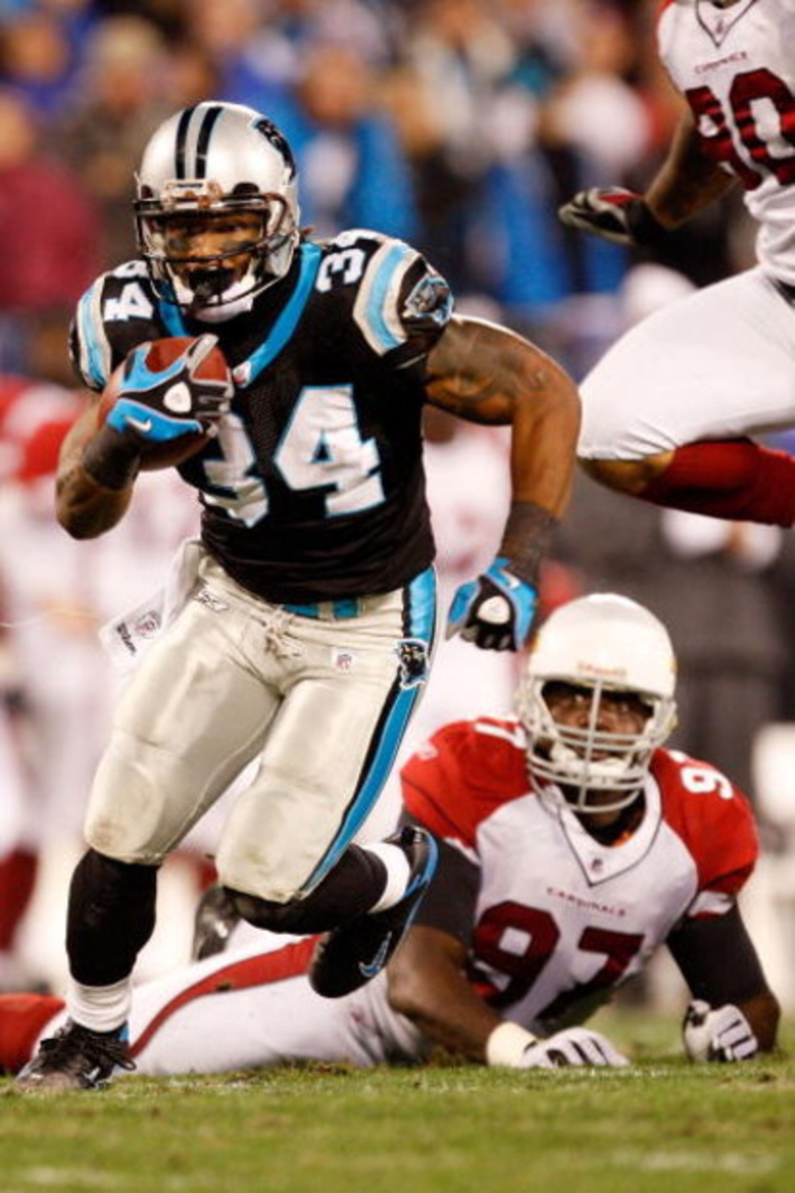 CHARLOTTE, NC - JANUARY 10:  DeAngelo Williams #34 of the Carolina Panthers runs the ball while Bryan Robinson #97 of the Arizona Cardinals looks on during the NFC Divisional Playoff Game on January 10, 2009 at Bank of America Stadium in Charlotte, North 