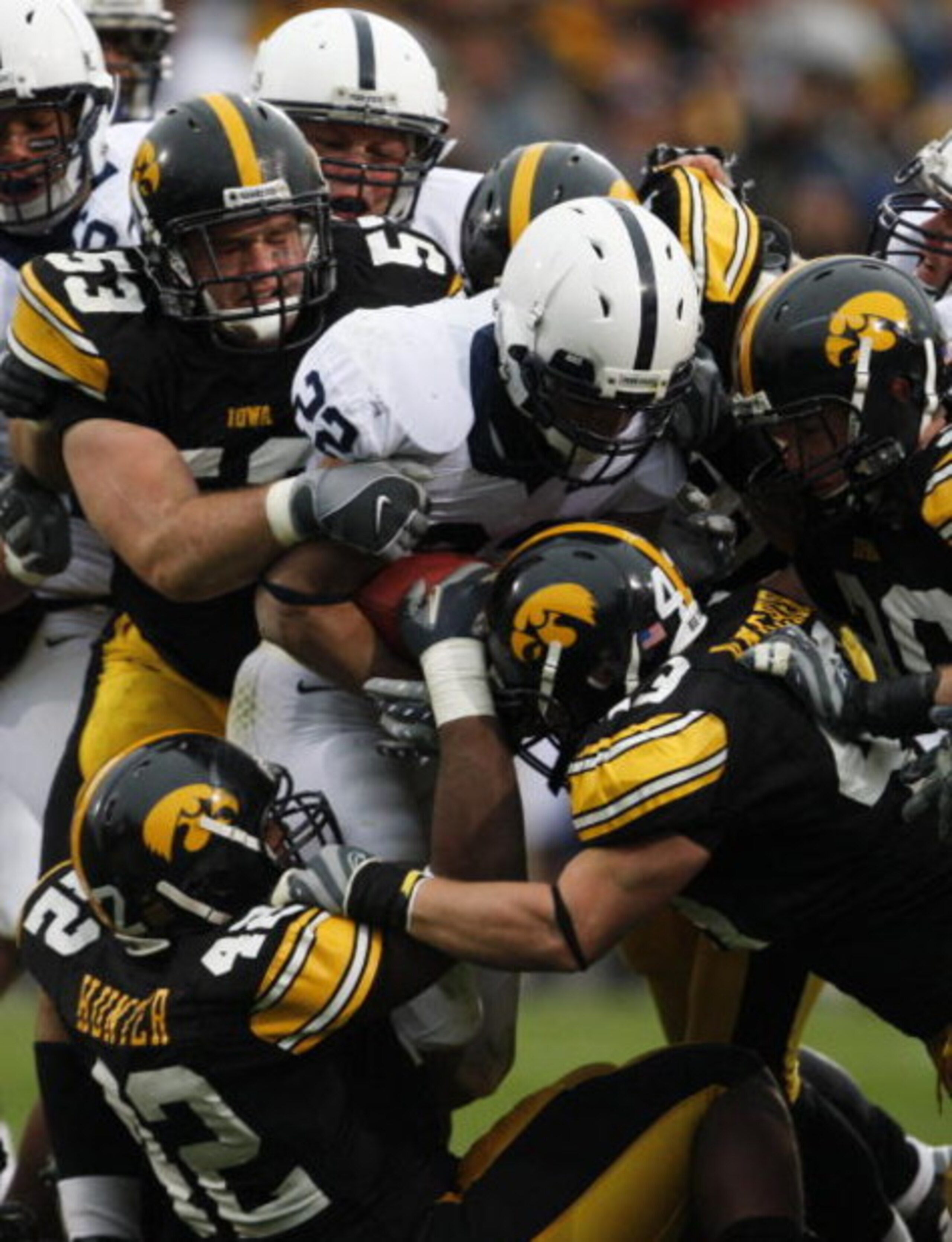 IOWA CITY, IA - NOVEMBER 8:  Defenders Matt Kroul #53, Pat Angerer #43 and Jeremiah Hunter #42 of the Iowa Hawkeyes tackle Evan Royster #22 of the Penn State Nittany Lions as he rushes for yards in the second quarter of play at Kinnick Stadium on November