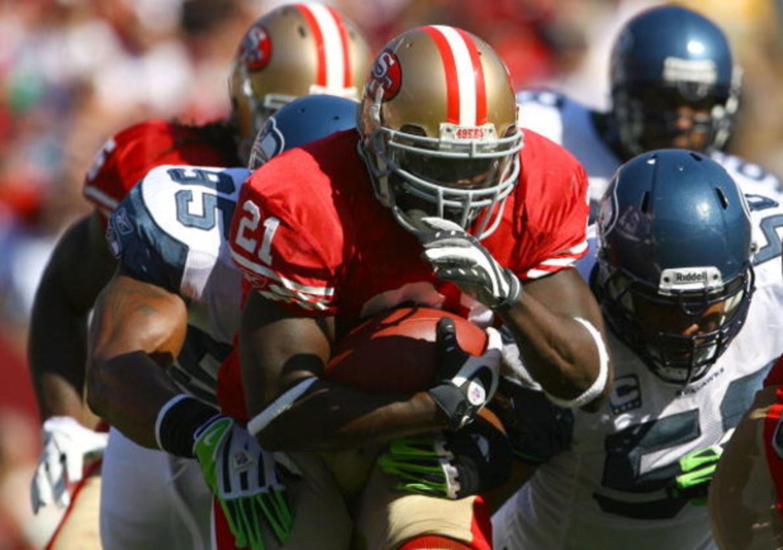 SAN FRANCISCO - OCTOBER 26:  Runningback Frank Gore #21 of the San Francisco 49ers carries the ball while being pursued by Lawrence Jackson #95 of the Seattle Seahawks in the first quarter at Candlestick Park on October 26, 2008 in San Francisco, Californ