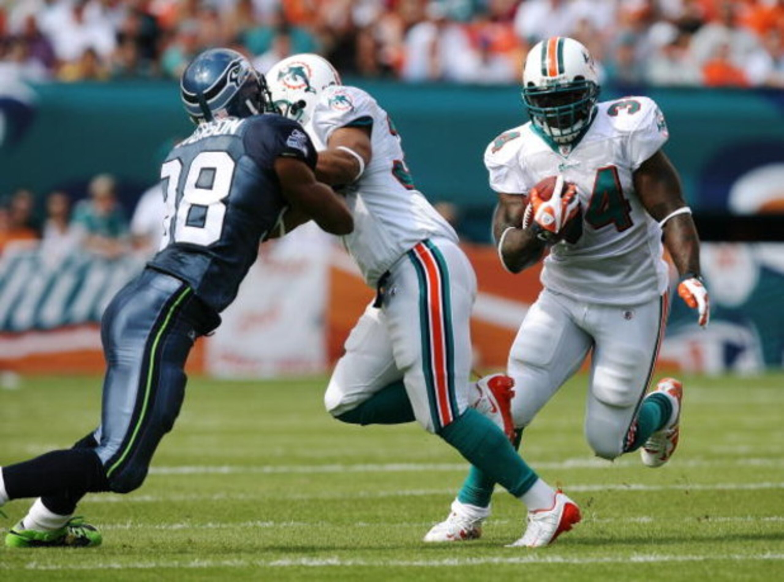 MIAMI - NOVEMBER 09:  Running back Ricky Williams #34 of the Miami Dolphins looks for room to run as fullback Lousaka Polite #36 blocks linebacker Julian Peterson #98 of the Seattle Seahawks at Dolphin Stadium on November 9, 2008 in Miami, Florida. The Do