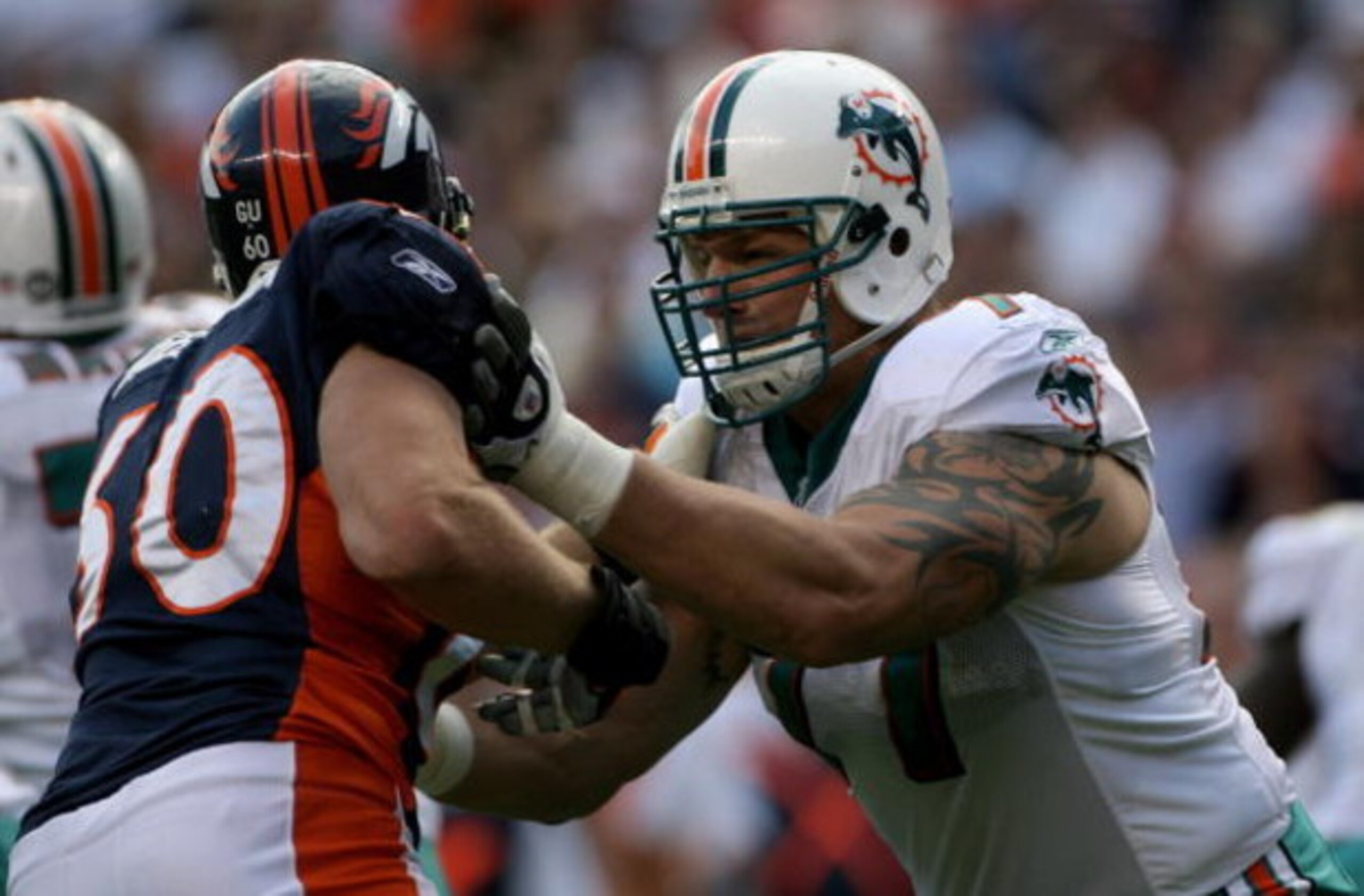 DENVER - NOVEMBER 02:  Offensive tackle Jake Long #77 of the Miami Dolphins blocks the rush of defensive end John Engelberger #60 of the Denver Broncos during NFL action at Invesco Field at Mile High on November 2, 2008 in Denver, Colorado. The Dolphins d