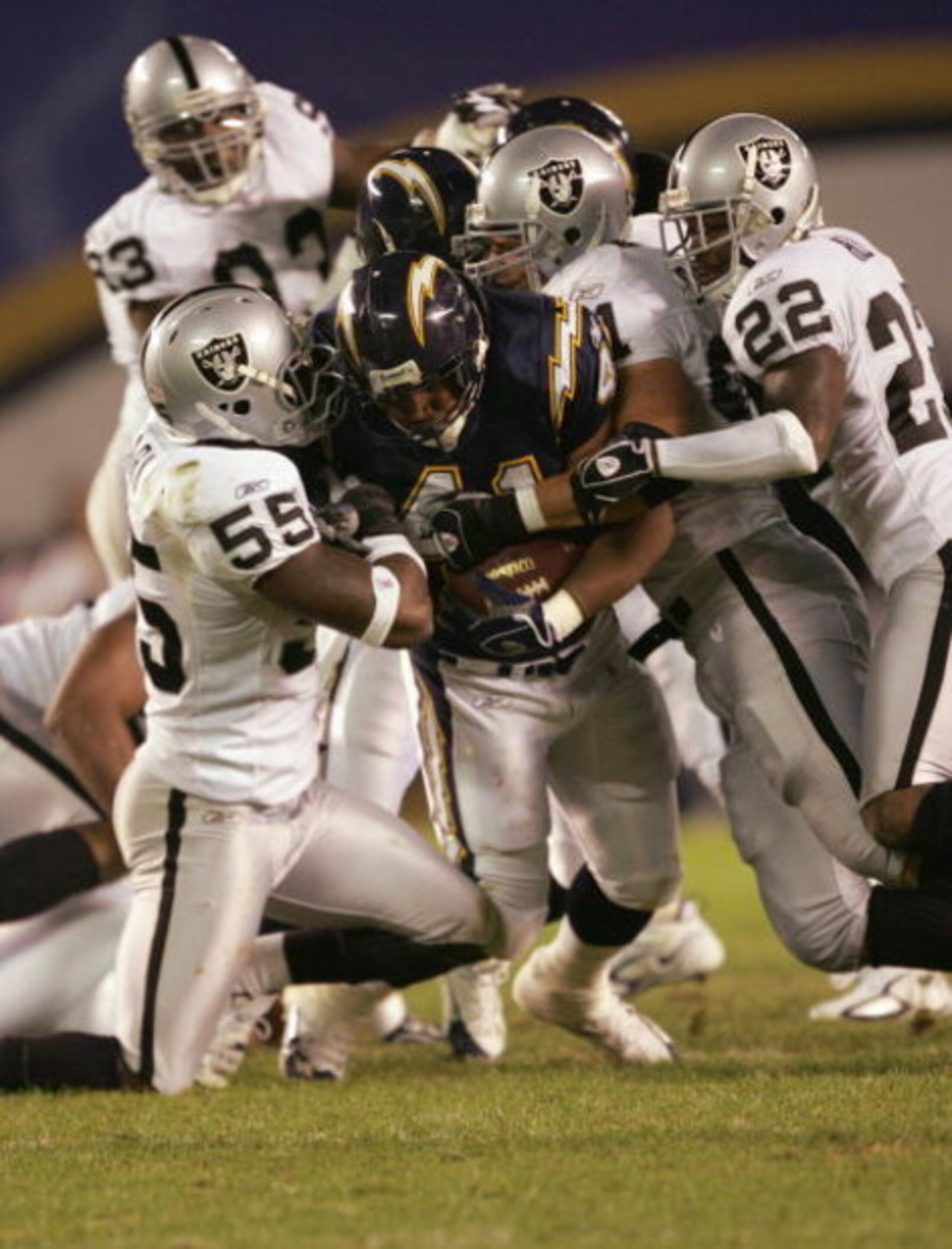 SAN DIEGO - DECEMBER 4:  Lorenzo Neal #41 of the San Diego Chargers grips the ball as he is tackled by Danny Clark #55 Renaldo Hill #22 of the Oakland Raiders on December 4, 2005 at Qualcomm Stadium in San Diego, California.  The Chargers won 34-10. (Phot
