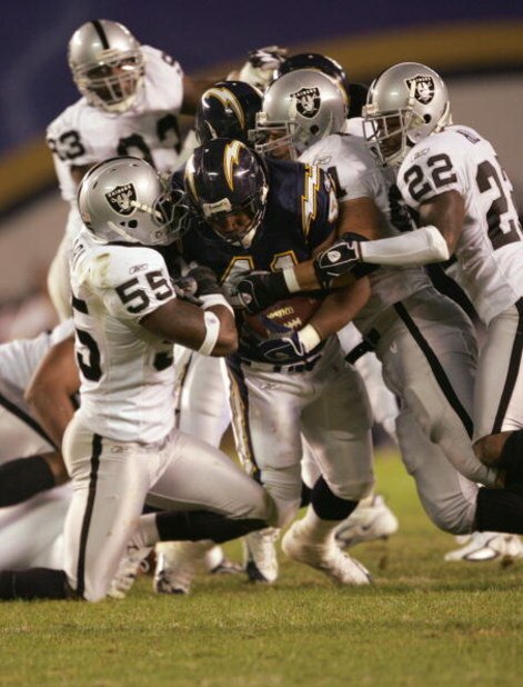 SAN DIEGO - DECEMBER 4:  Lorenzo Neal #41 of the San Diego Chargers grips the ball as he is tackled by Danny Clark #55 Renaldo Hill #22 of the Oakland Raiders on December 4, 2005 at Qualcomm Stadium in San Diego, California.  The Chargers won 34-10. (Phot