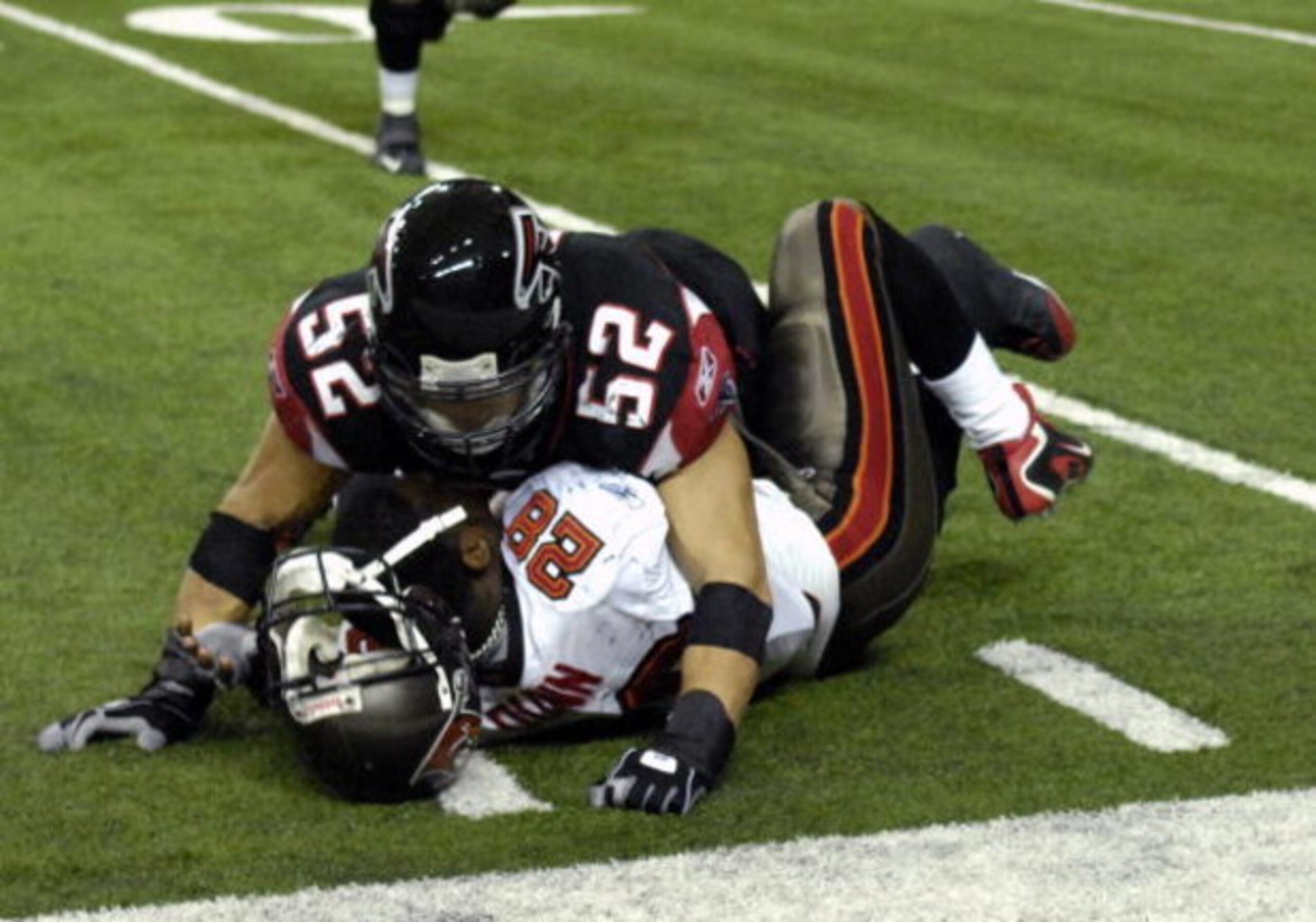 ATLANTA - DECEMBER 14: Linebacker Coy Wire #52 of the Atlanta Falcons knocks the helmet off of running back Warrick Dunn #28 of the Tampa Bay Buccaneers at the Georgia Dome on December 14, 2008 in Atlanta, Georgia.  (Photo by Al Messerschmidt/Getty Images