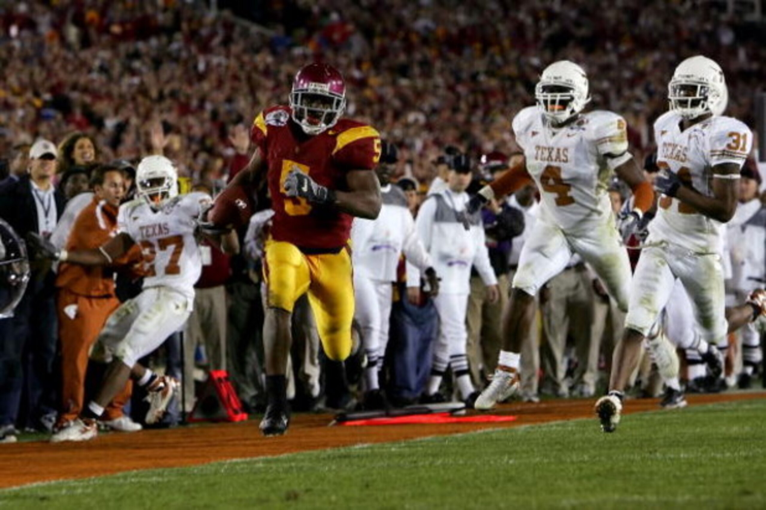 PASADENA, CA - JANUARY 04:  Reggie Bush #5 of the USC Trojans runs past Michael Griffin #27, Drew Kelson #4 and Aaron Ross #31 of the Texas Longhorns en route to scoring a 26 yeard touchdown in the fourth quarter of the BCS National Championship Rose Bowl