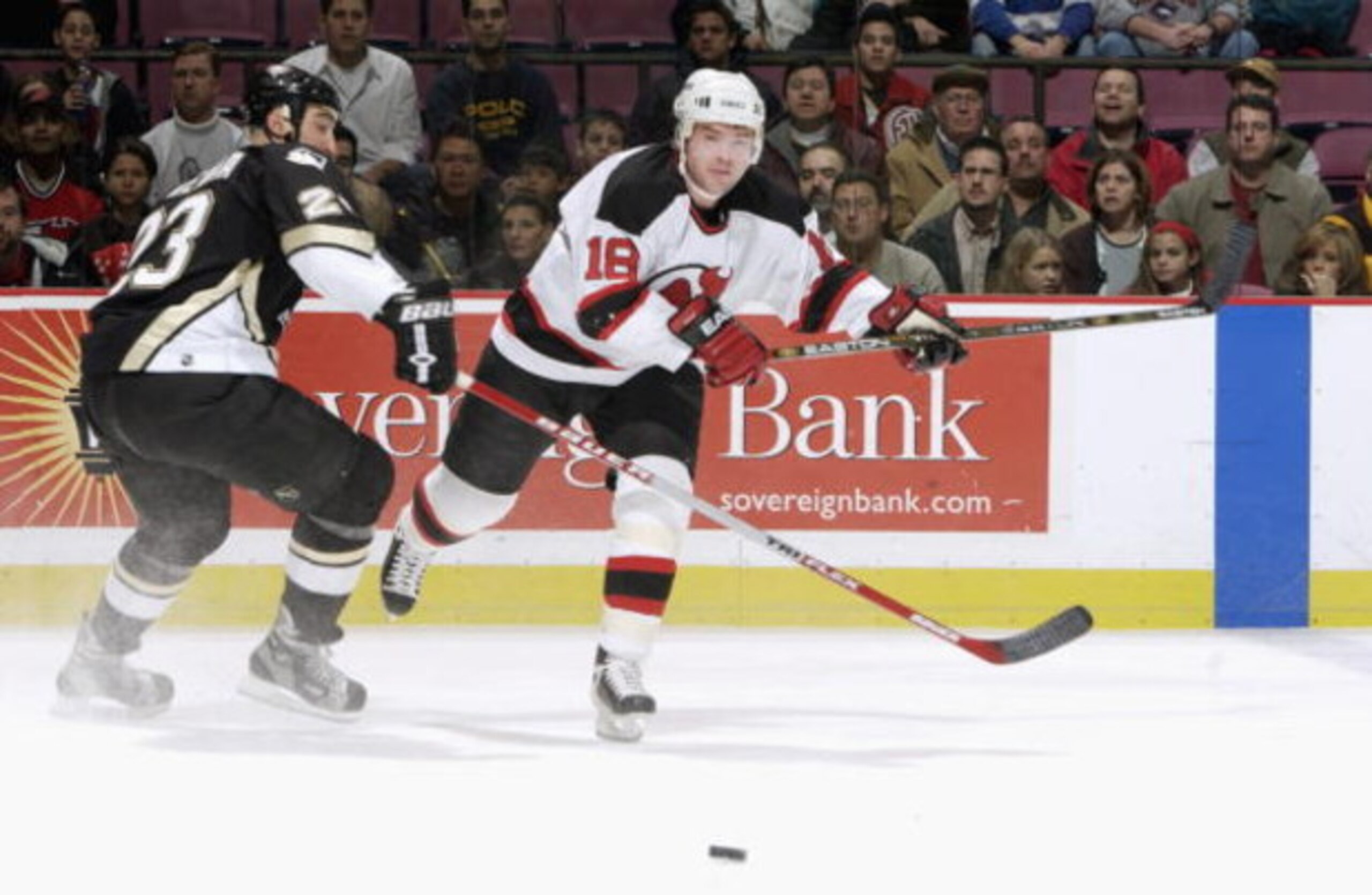 EAST RUTHERFORD, NJ - DECEMBER 6:  Center Sergei Brylin #18 of the New Jersey Devils chases down the puck while being defended by left wing Steve McKenna #23 of the Pittsburgh Penguins at Continental Airlines Arena on December 6, 2002 in East Rutherford, 