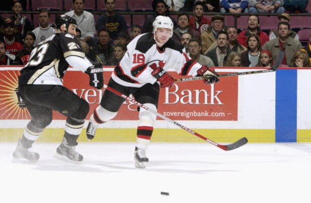 EAST RUTHERFORD, NJ - DECEMBER 6:  Center Sergei Brylin #18 of the New Jersey Devils chases down the puck while being defended by left wing Steve McKenna #23 of the Pittsburgh Penguins at Continental Airlines Arena on December 6, 2002 in East Rutherford, 