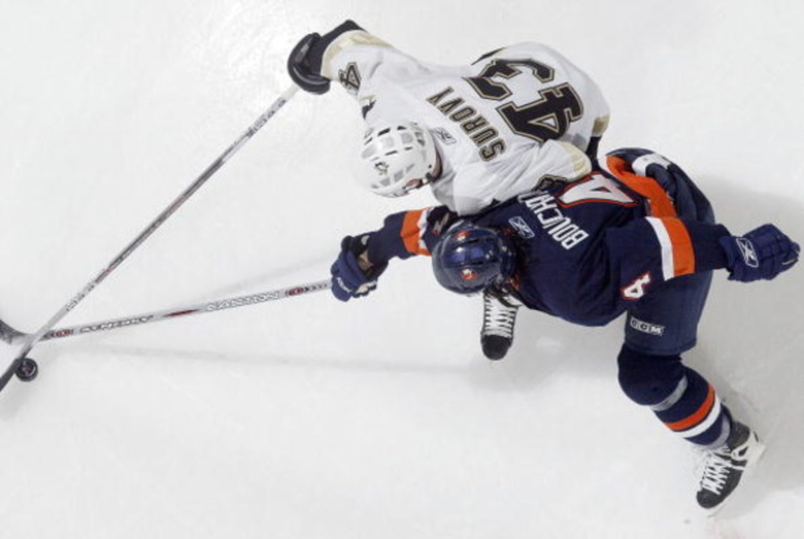 UNIONDALE, NY - JANUARY 26:  Joel Bouchard #4 of the New York Islanders reaches for the puck against Tomas Surovy #43 of the Pittsburgh Penguins during their NHL game on January 26, 2006 at Nassau Coliseum in Uniondale, New York. The Isles defeated the Pe