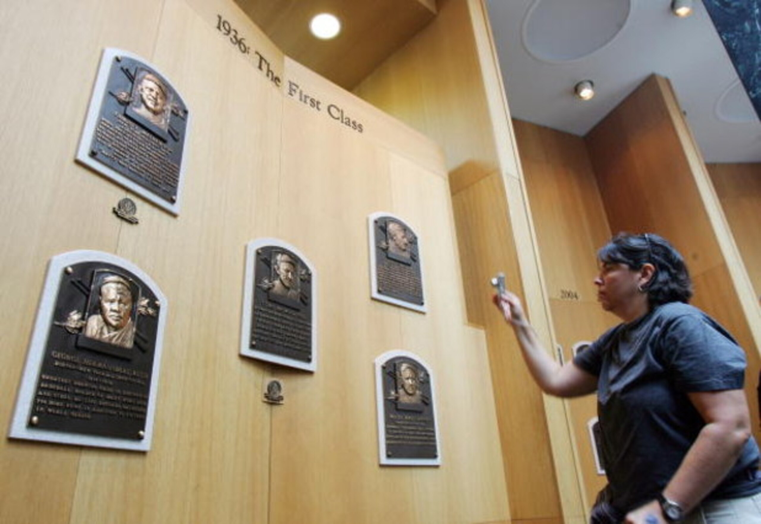 COOPERSTOWN, NY - JULY 26:  A baseball fan photographs plaques of the first five players inducted into the National Baseball Hall of Fame and Museum during the Baseball Hall of Fame weekend on July 26, 2008 in Cooperstown, New York.  (Photo by Jim McIsaac