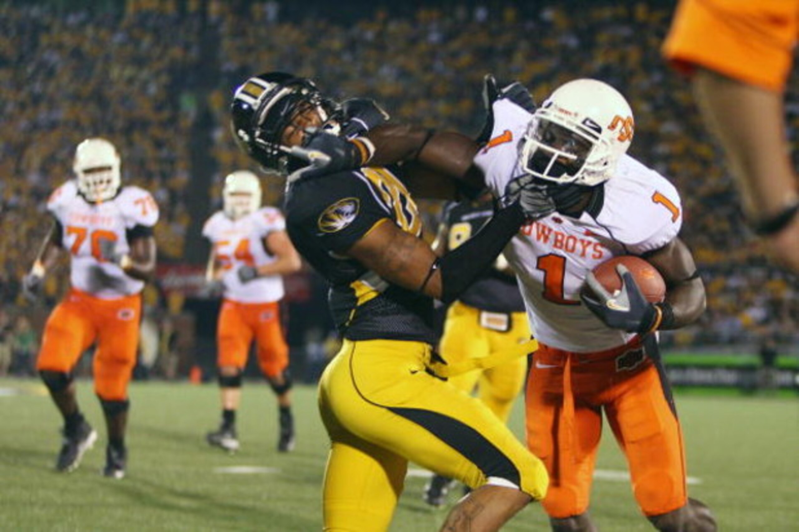 COLUMBIA, MO - OCTOBER 11:  Dez Bryant #1 of the Oklahoma State Cowboys stiff-arms Castine Bridges #21 of the Missouri Tigers  on October 11, 2008 at Memorial Stadium in Columbia, Missouri.  (Photo by G. Newman Lowrance/Getty Images)