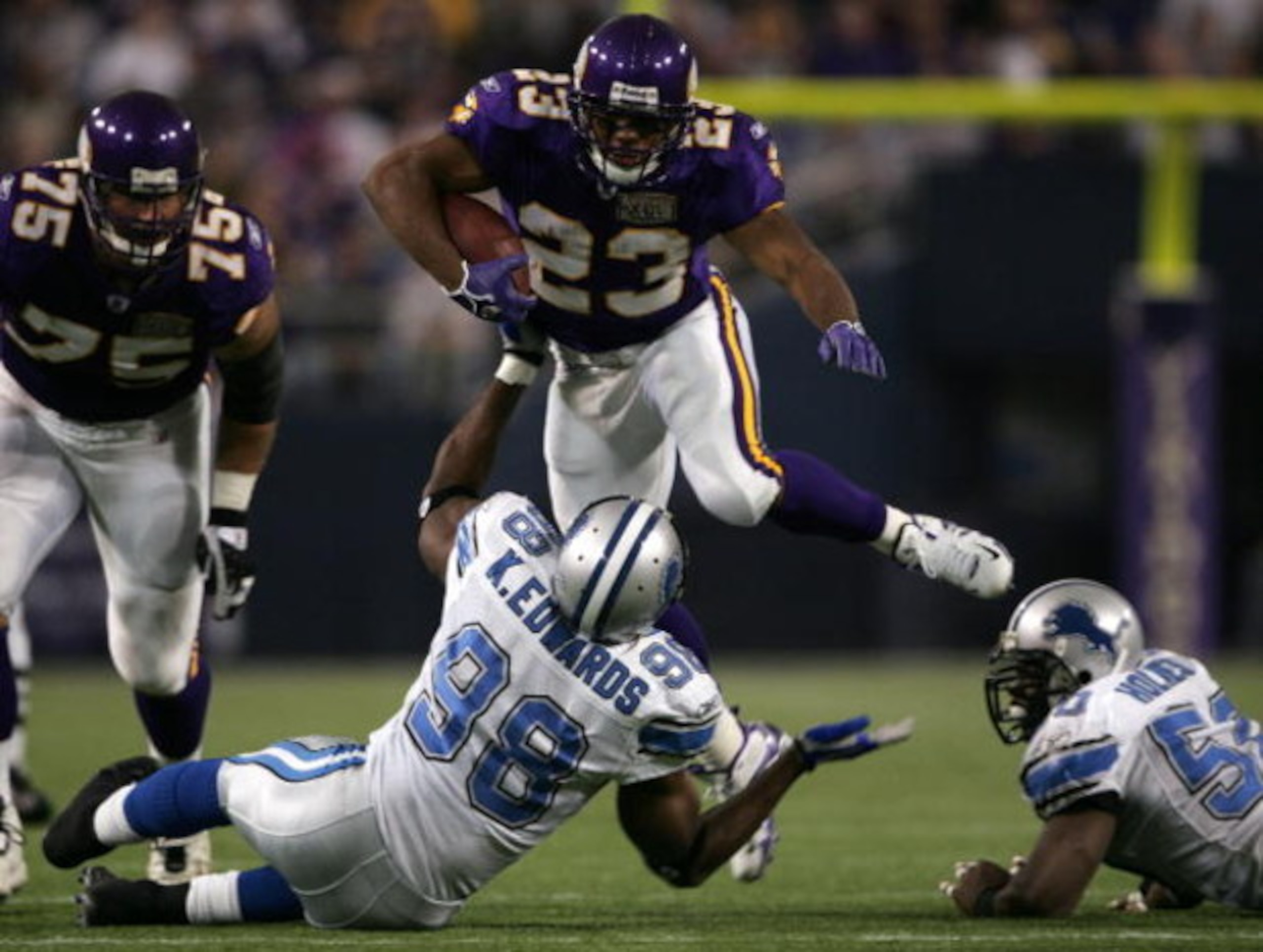 MINNEAPOLIS - NOVEMBER 6:  Michael Bennett #23 of the Minnesota Vikings leaps over Kalimba Edwards #98 of the the Detroit Lions on November 6, 2005 at the Hubert H. Humphrey Metrodome in Minneapolis, Minnesota.  (Photo by Elsa/Getty Images)