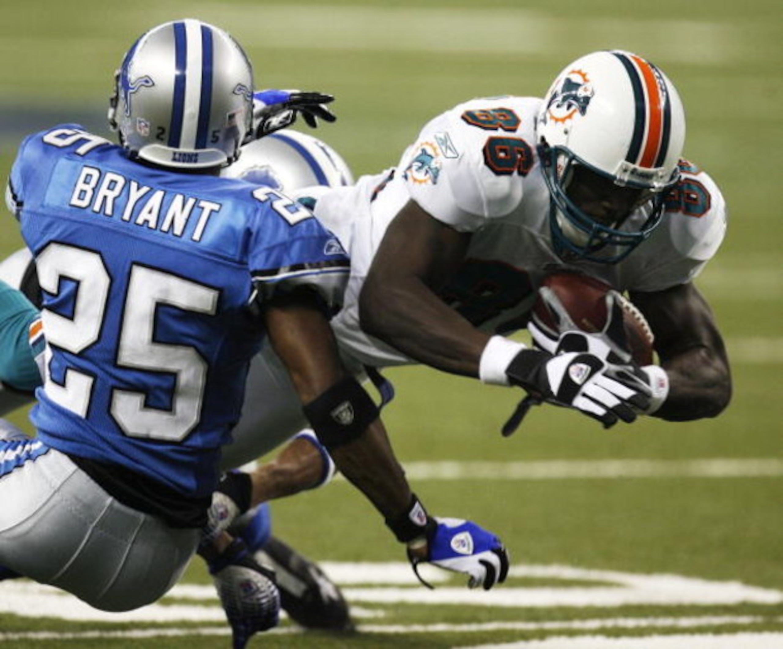 DETROIT , MI - NOVEMBER 23:  Marty Booker #86 of the Miami Dolphins dives past the tackle of Fernando Bryant #25 of the Detroit Lions during second quarter action on November 23, 2006 at Ford Field in Detroit, Michigan. Miami won the game 27-10.  (Photo b