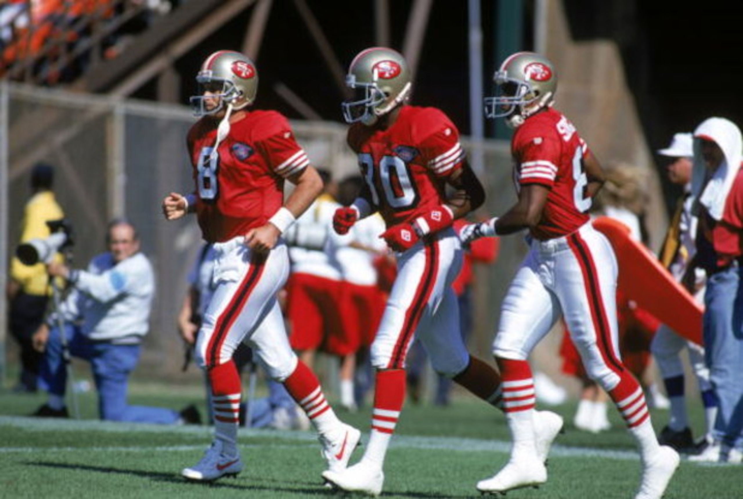 SAN FRANCISCO - SEPTEMBER 24:  (L-R) Quarterback Steve Young #8, wide receivers Jerry Rice #80 and Nate Singleton #88 of the San Francisco 49ers run on the field during a game against the New Orleans Saints at Candlestick Park on September 24, 1994 in San