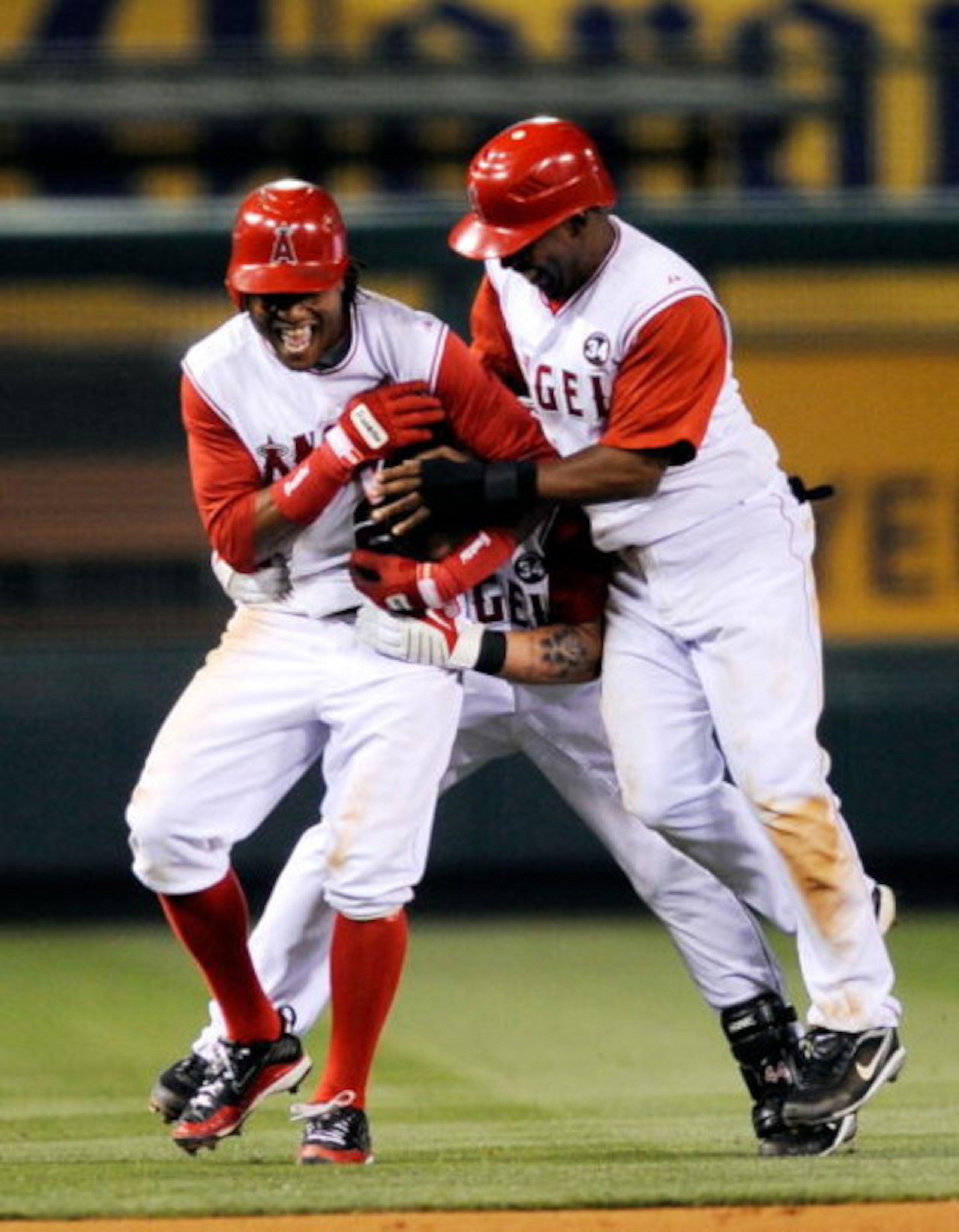 ANAHEIM, CA - JULY 23:  Mike Napoli #44 (C) of the Los Angeles Angels of Anaheim is congratulated by Eric k Aybar #2 (L) and  Chone Figgins #9 after hitting the game winning double to score Figgins against the Minnesota Twins during the 10th inning of the