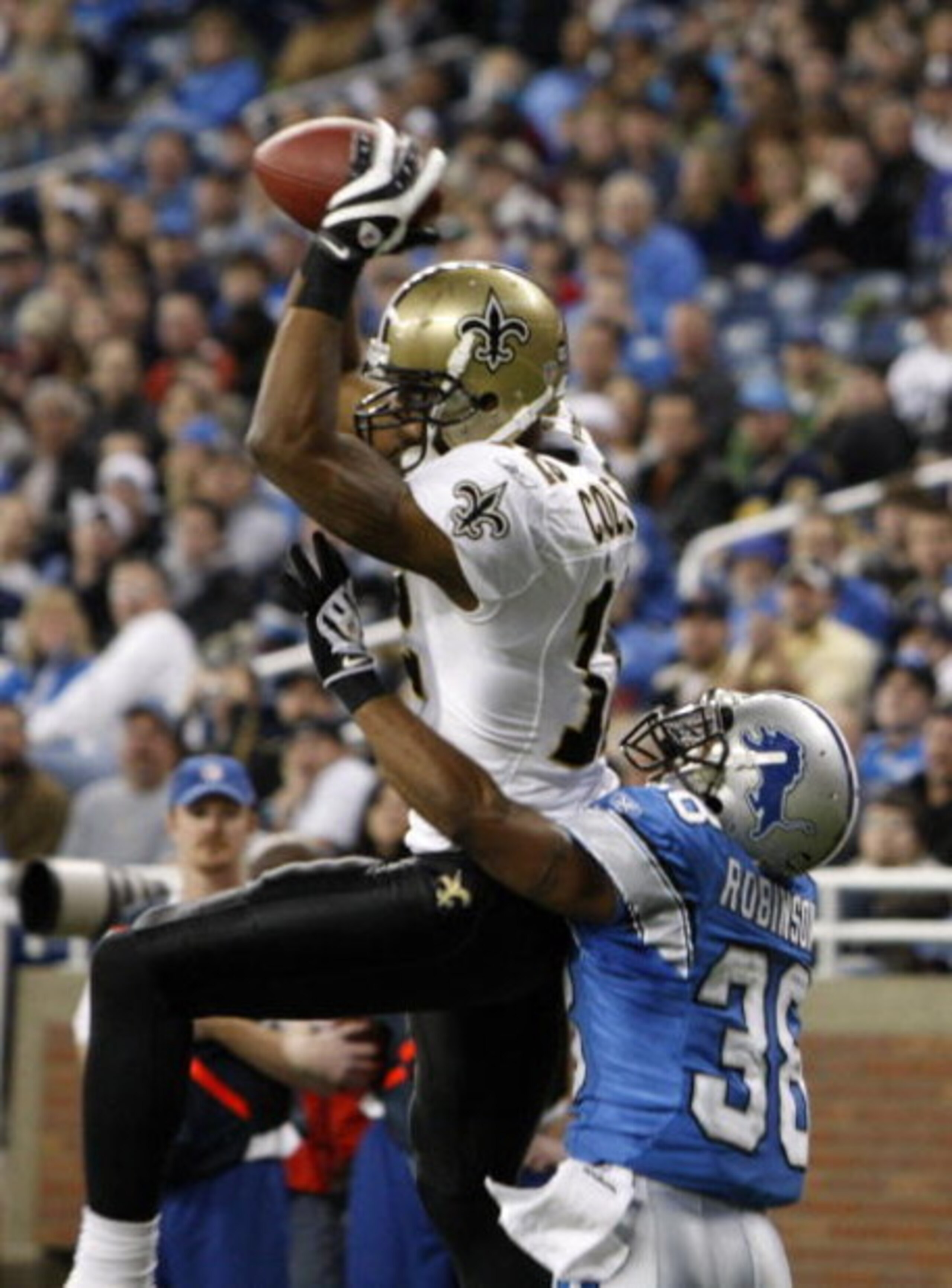 DETROIT - DECEMBER 21:  Wide receiver Marques Colston #12 of the New Orleans Saints scores on a six yard pass in the third quarter as Detroit Lions cornerback Ramzee Robinson #38 attempts to defend on December 21, 2008 at Ford Field in Detroit, Michigan. 