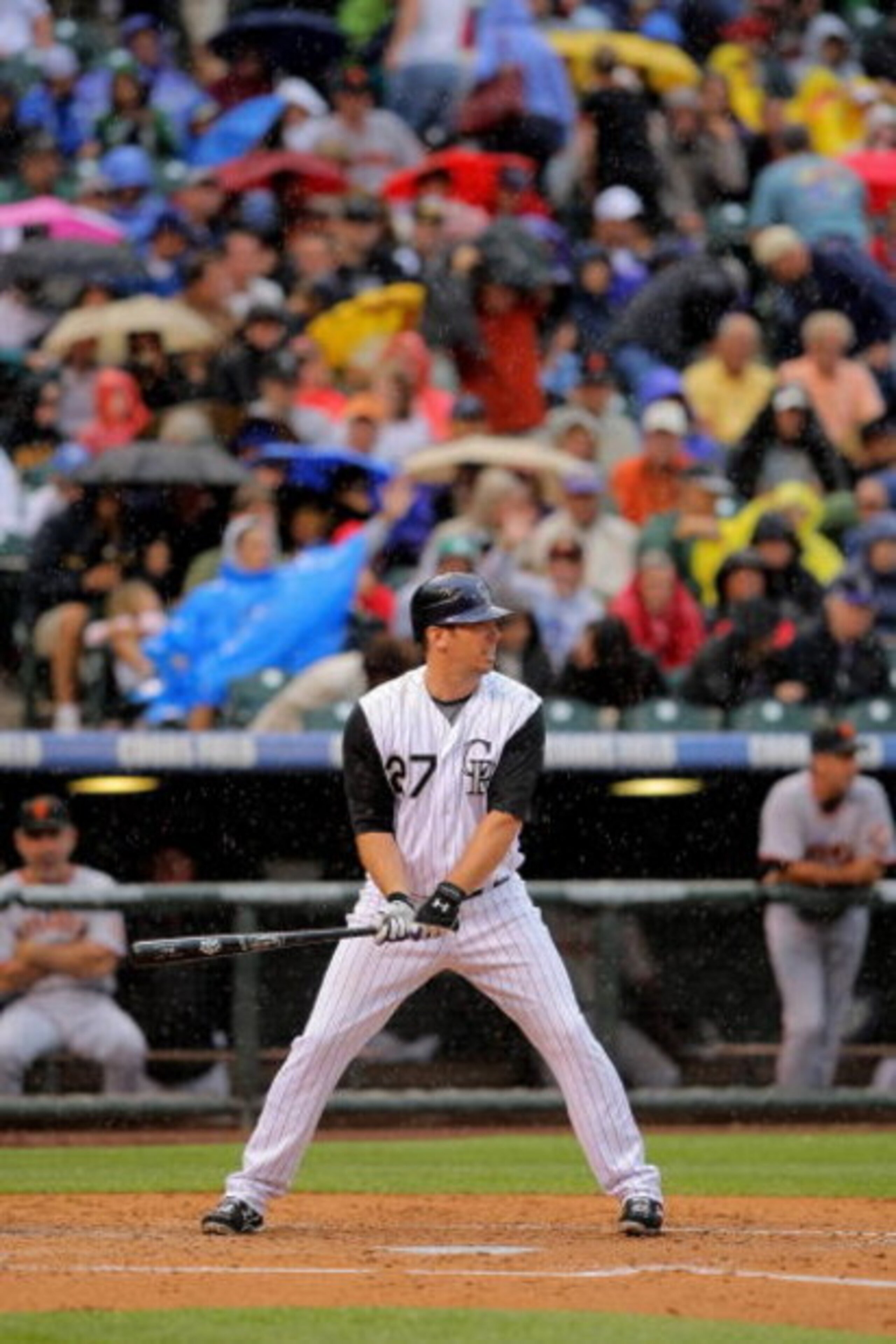 DENVER - JULY 25:  Garrett Atkins #27 of the Colorado Rockies takes an at bat as fans protect themselves from the rain with umbrellas against the San Francisco Giants at Coors Field on July 25, 2009 in Denver, Colorado. The Rockies defeated the Giants 8-2