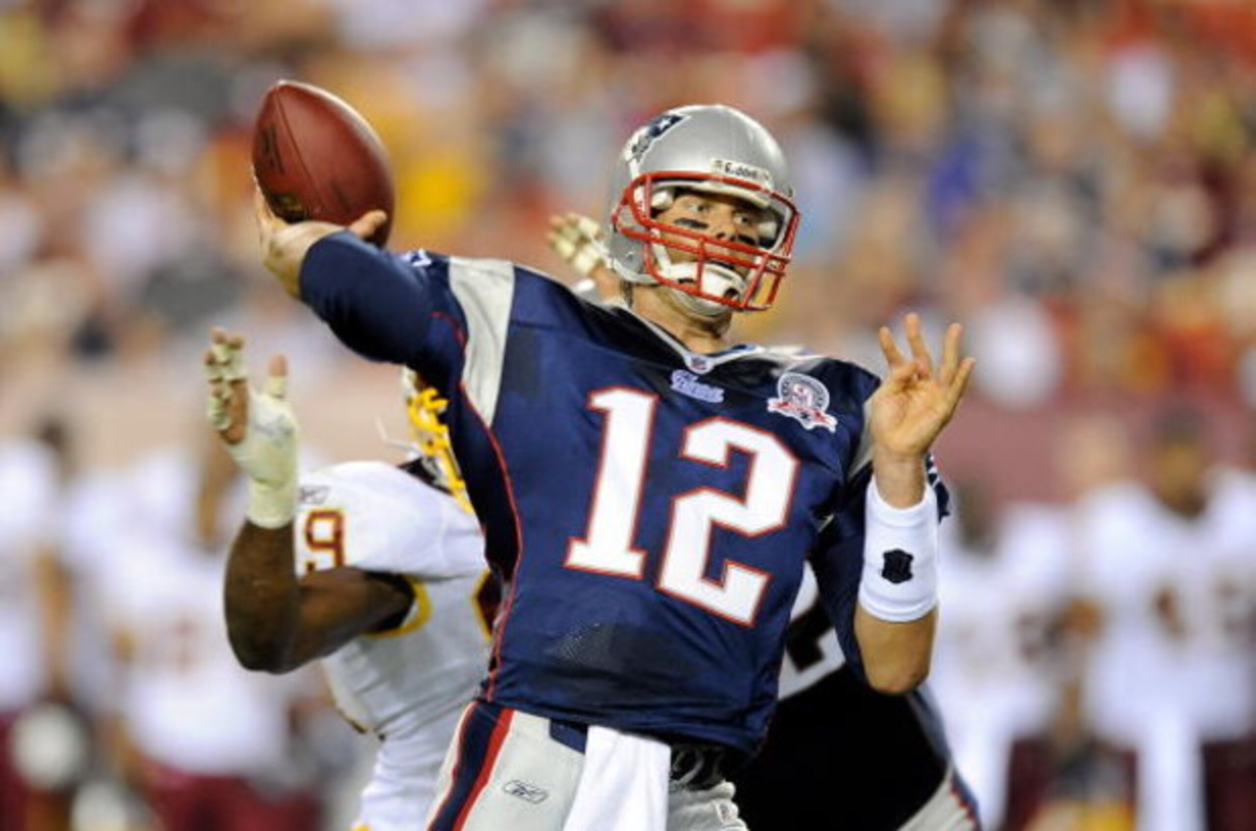 LANDOVER, MD - AUGUST 28:  Tom Brady #12 of the New England Patriots throws a touchdown to Randy Moss #81 (not pictured) in the first quarter of a preseason game against the Washington Redskins at FedExField on August 28, 2009 in Landover, Maryland.  (Pho