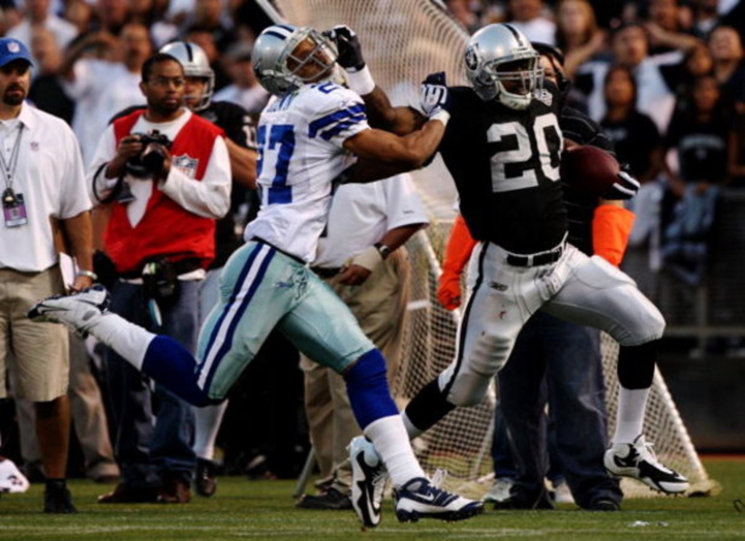 OAKLAND, CA - AUGUST 13:  Running back Darren McFadden #20 of the Oakland Raiders gives a stiff arm during a second quarter run against Courtney Brown #27 of the Dallas Cowboys during the preseason game at Oakland-Alameda County Coliseum on August 13, 200