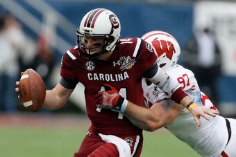 ORLANDO, FL - JANUARY 01:  Connor Shaw #14 of the South Carolina Gamecocks is pressured by Brendan Kelly #97 of the Wisconsin Badgers  during the first half of their game against the Wisconsin Badgers at the Capital One Bowl on January 1, 2014 in Orlando,