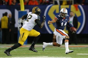 ATLANTA, GA - DECEMBER 07:  Nick Marshall #14 of the Auburn Tigers runs the ball against Darvin Ruise #12 of the Missouri Tigers during the SEC Championship Game at Georgia Dome on December 7, 2013 in Atlanta, Georgia.  (Photo by Mike Ehrmann/Getty Images
