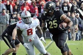 Nov 2, 2013; West Lafayette, IN, USA;  Purdue Boilermakers running back Brandon Cottom (25) runs past Ohio State Buckeyes defensive lineman Noah Spence (8) in the first half at Ross Ade Stadium. Mandatory Credit: Sandra Dukes-USA TODAY Sports