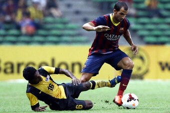 KUALA LUMPUR, MALAYSIA - AUGUST 10:  Martin Montoya of Barcelona FC is tackled by S. Kunanalan of Malaysia during the friendly match between FC Barcelona and Malaysia at the Shah Alam Stadium on August 10, 2013 in Kuala Lumpur, Malaysia.  (Photo by Stanle