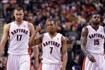 Jan 1, 2014; Toronto, Ontario, CAN; Toronto Raptors point guard Kyle Lowry (7) and center Jonas Valanciunas (17) and power forward Amir Johnson (15) react to a play during the fourth quarter of a game at the Air Canada Centre. Toronto won the game  95-82.