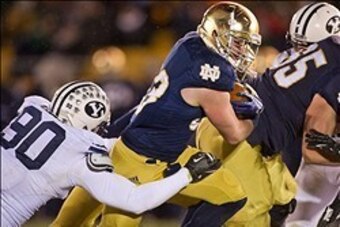 Nov 23, 2013; South Bend, IN, USA; Notre Dame Fighting Irish running back Cam McDaniel (33) carries the ball as BYU Cougars defensive lineman Bronson Kaufusi (90) defends in the third quarter at Notre Dame Stadium. Notre Dame won 23-13. Mandatory Credit: 