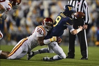 Nov 30, 2013; Morgantown, WV, USA; Iowa State Cyclones defensive end Willie Scott (50) sacks and strips the ball from West Virginia Mountaineers quarterback Clint Trickett (9) during the second quarter at Milan Puskar Stadium. Mandatory Credit: Tommy Gill